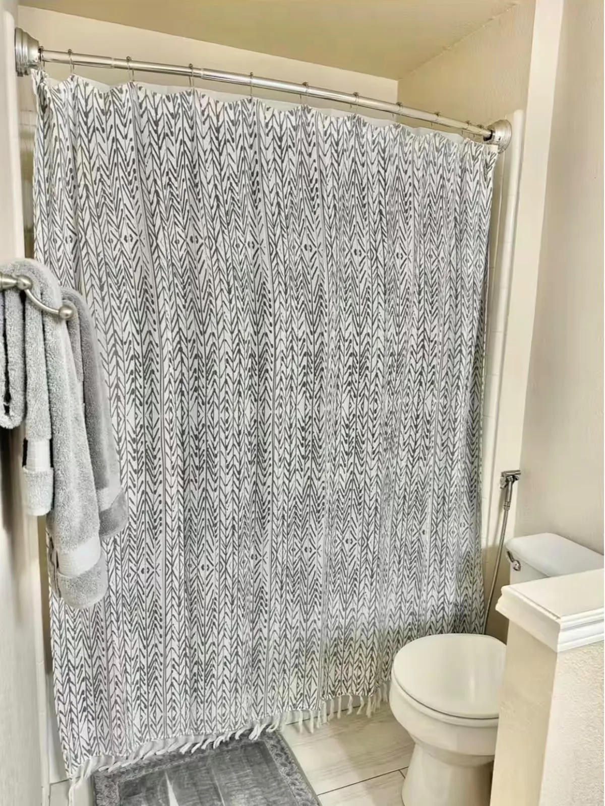 Bathroom featuring a curved shower rod, a built-in toilet, and light-toned flooring