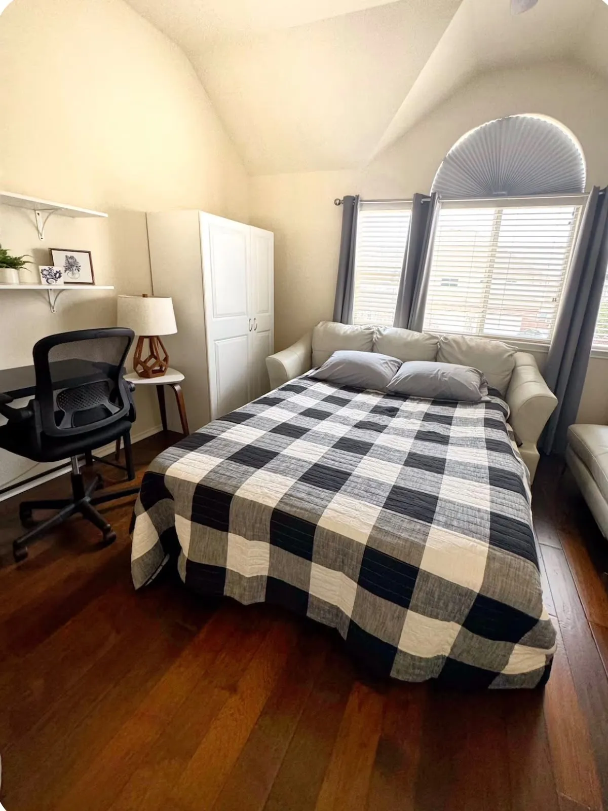 Vaulted ceiling room featuring rich wood-finish flooring, a wall-mounted shelving unit, and a built-in storage cabinet