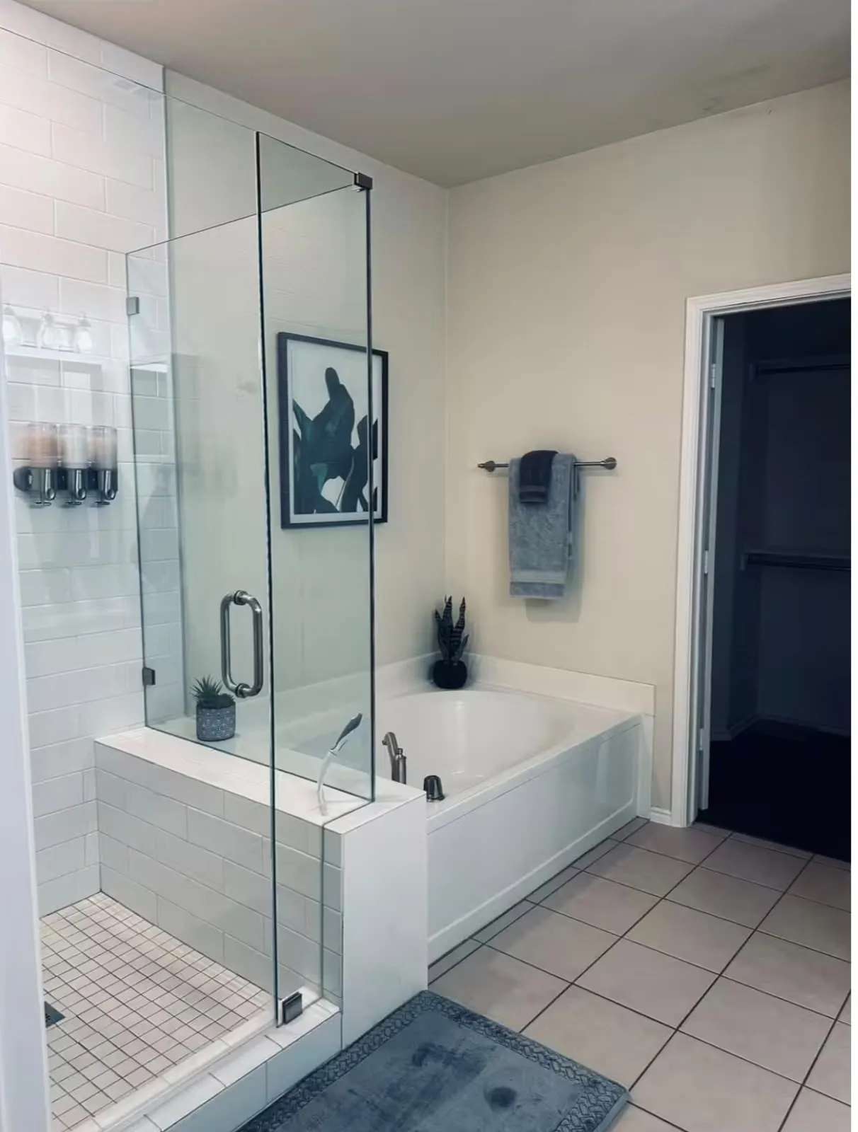 Bathroom with a glass-enclosed shower featuring white subway tile, a built-in soaking tub, and neutral-toned wall paint