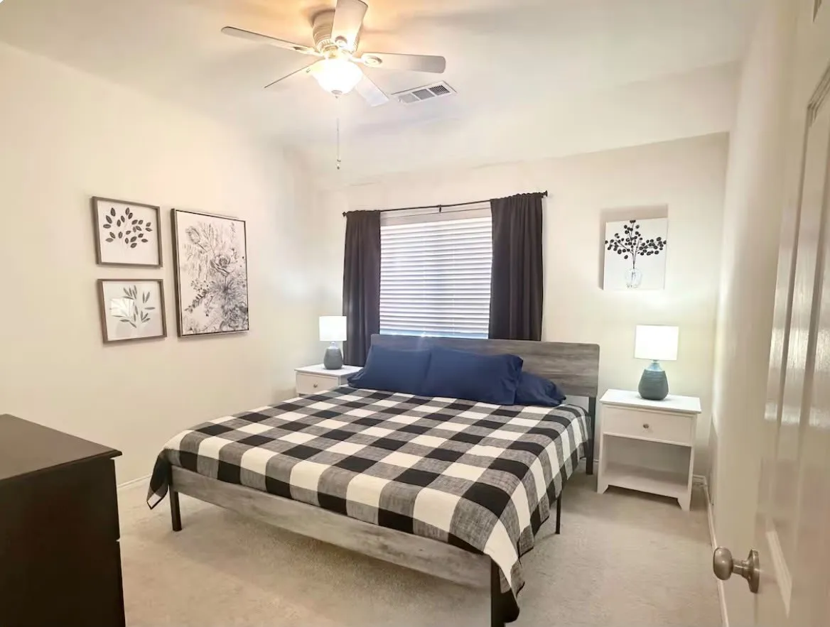 Bedroom featuring carpet flooring, a window with blinds and dark curtains, and a ceiling fan with integrated lighting