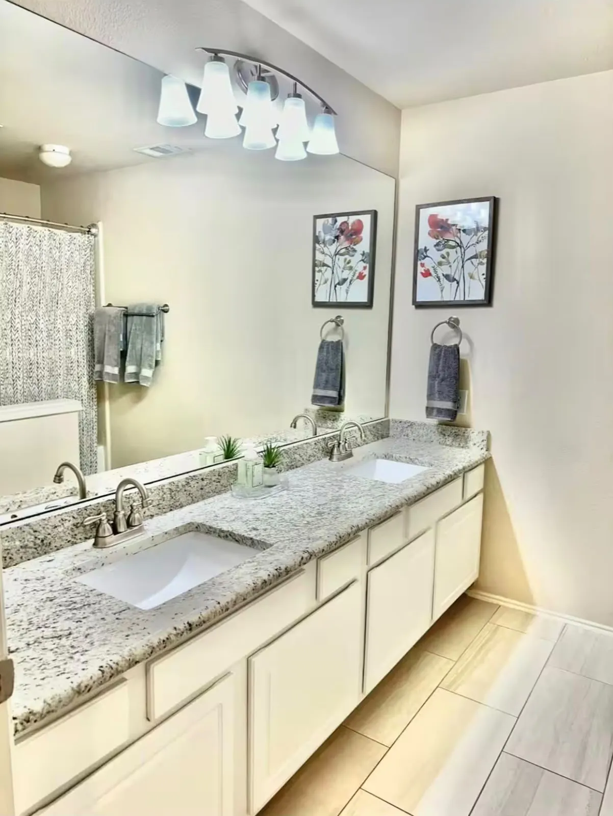 Dual vanity with granite-finish countertops, white cabinetry, and brushed nickel fixtures