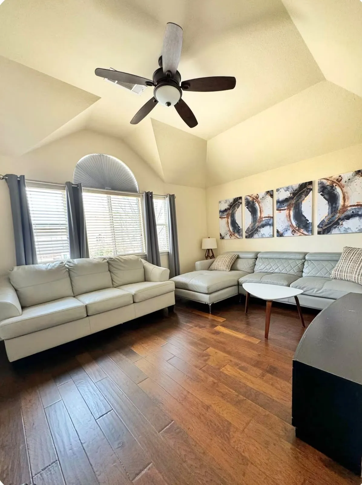 Vaulted ceiling with an overhead fan and recessed lighting, wood-finish flooring, and multiple windows with an arched transom