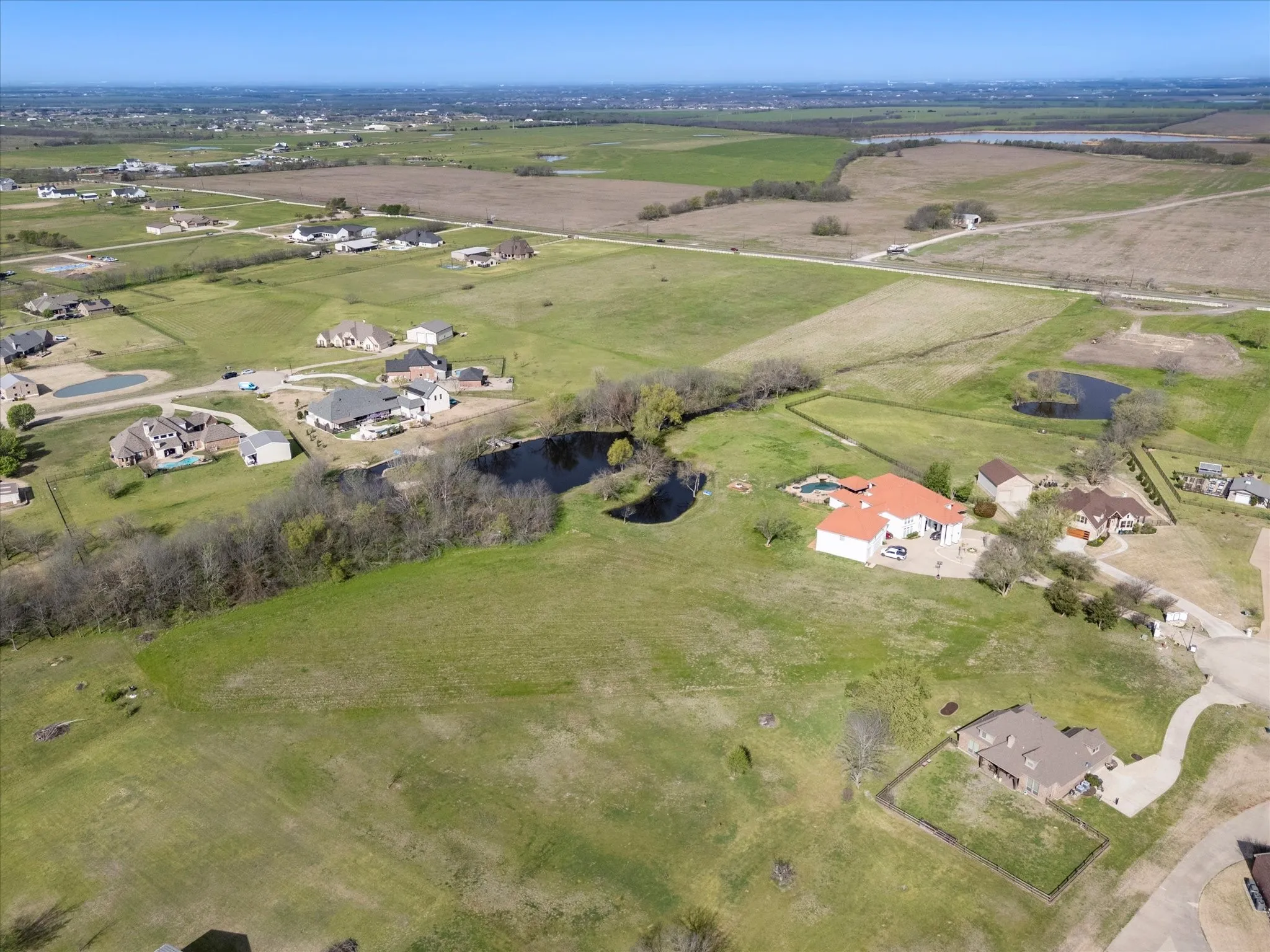 Expansive aerial landscape featuring a residential property with a terracotta roof, a swimming pool, and a private pond