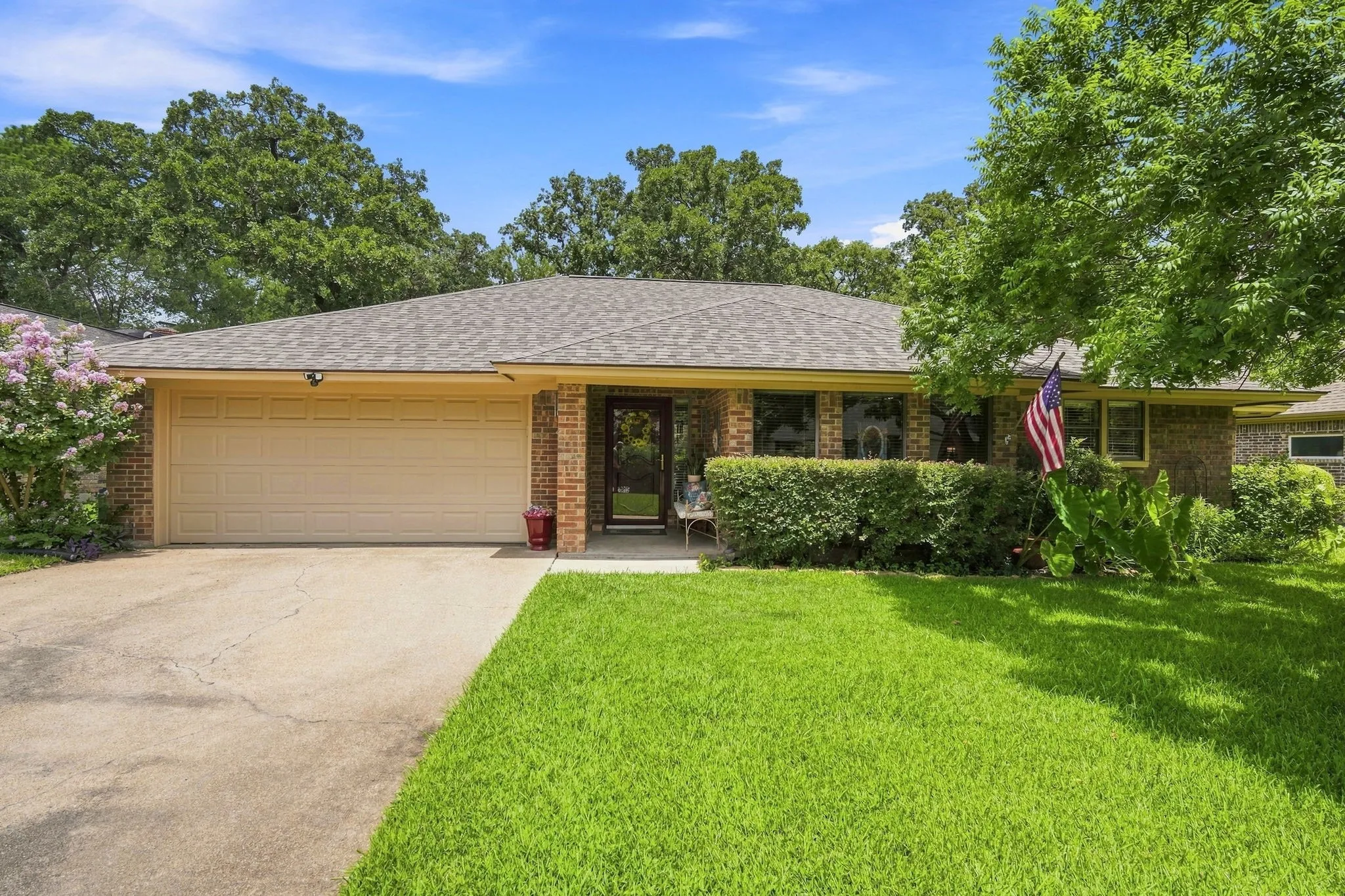 Brick-front home featuring a two-car garage, concrete driveway, and a shingle roof