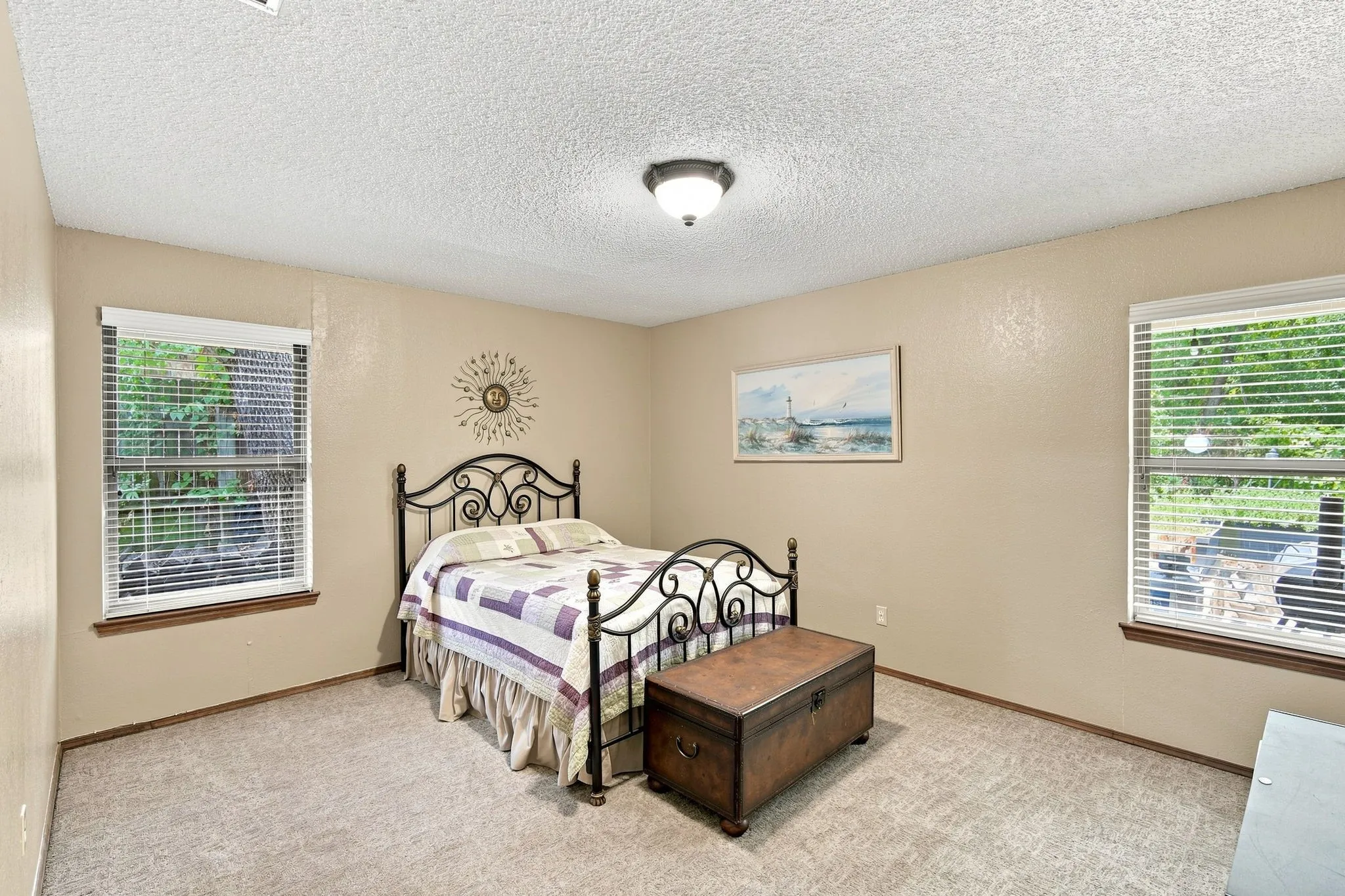 Spacious room featuring neutral wall tones, textured ceiling, and plush carpeting