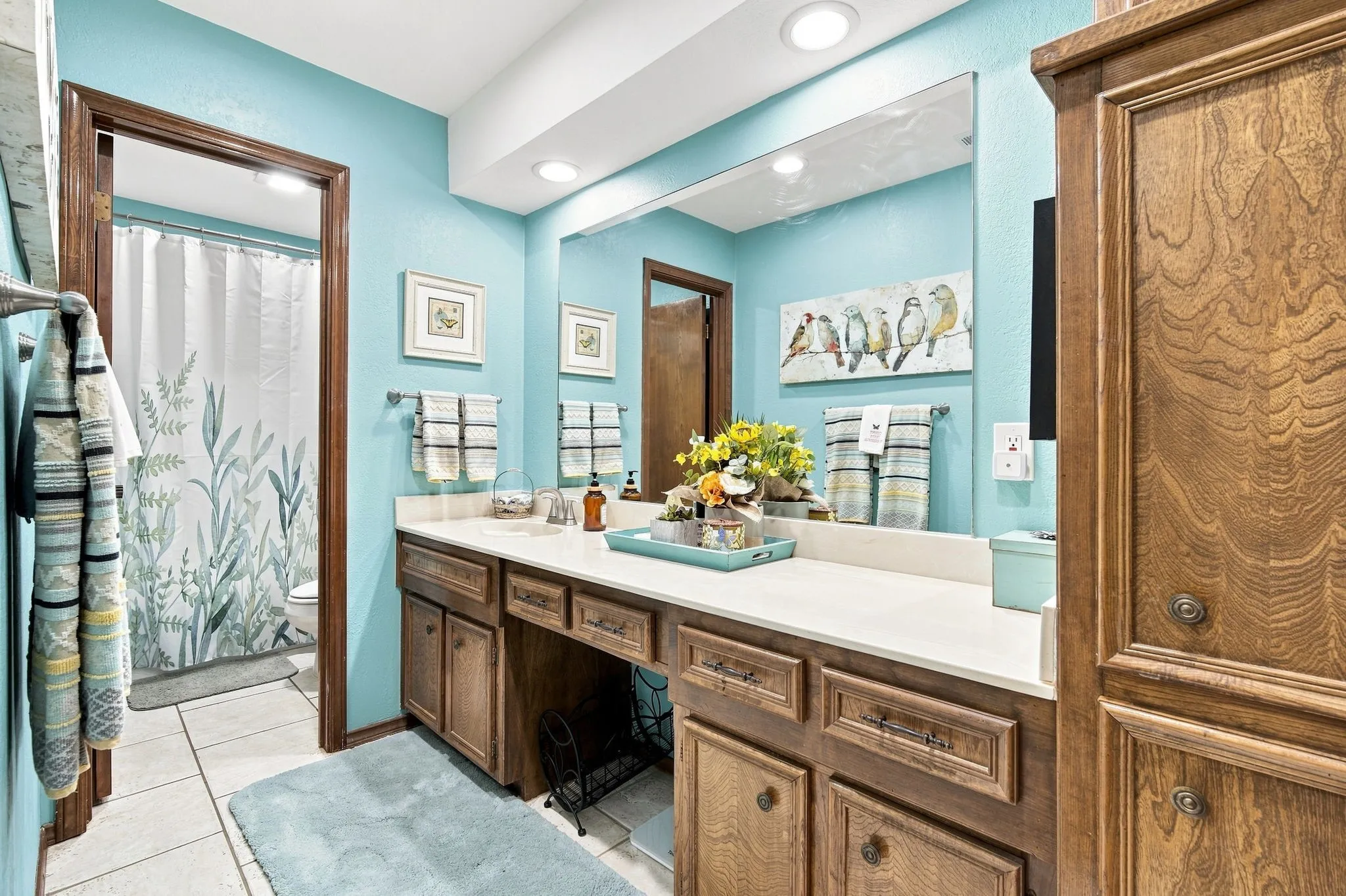 Bathroom vanity featuring a light-colored countertop, integrated sink, and wood cabinetry with multiple storage options