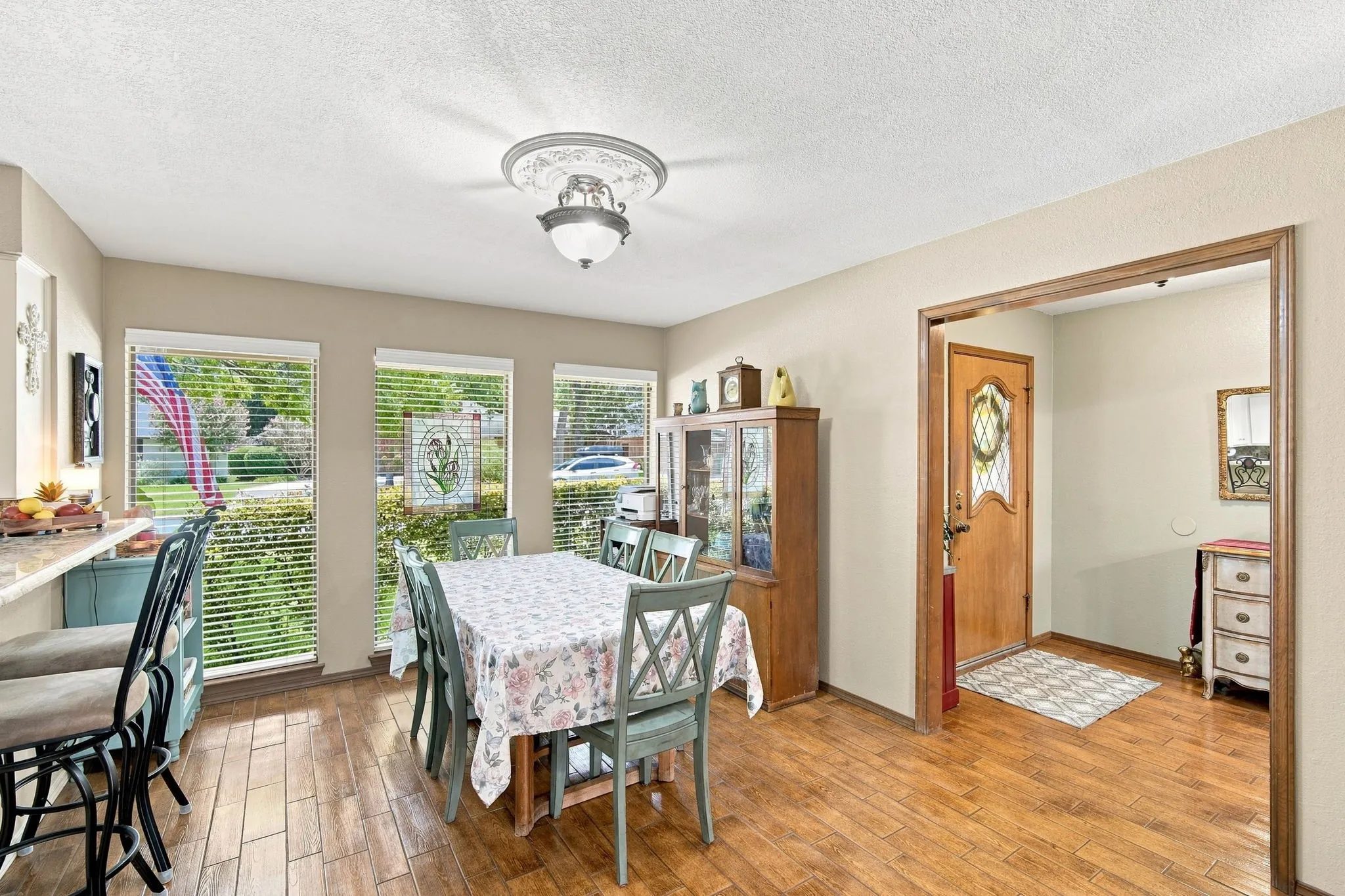 Dining area featuring wood-finish flooring, a decorative ceiling fixture, and multiple windows with blinds