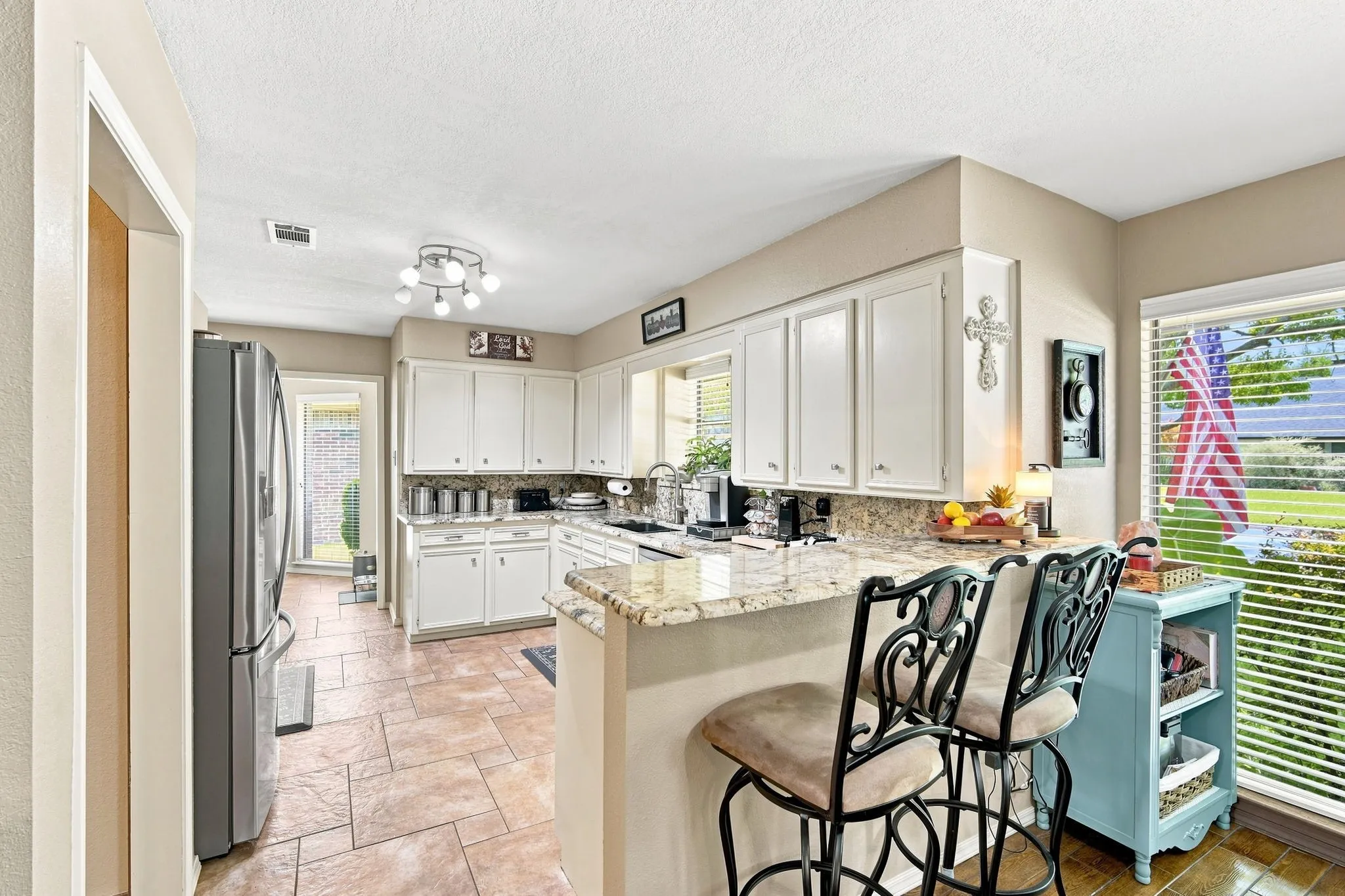 Kitchen featuring white cabinetry, light-toned countertops, and durable tile flooring