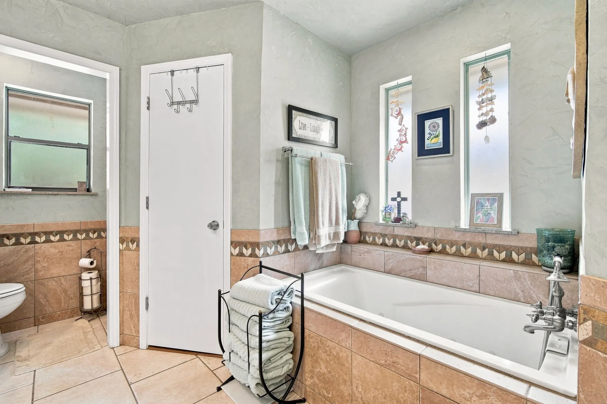 Spacious bathroom featuring a built-in soaking tub, decorative tile surround, and light-toned wall finishes