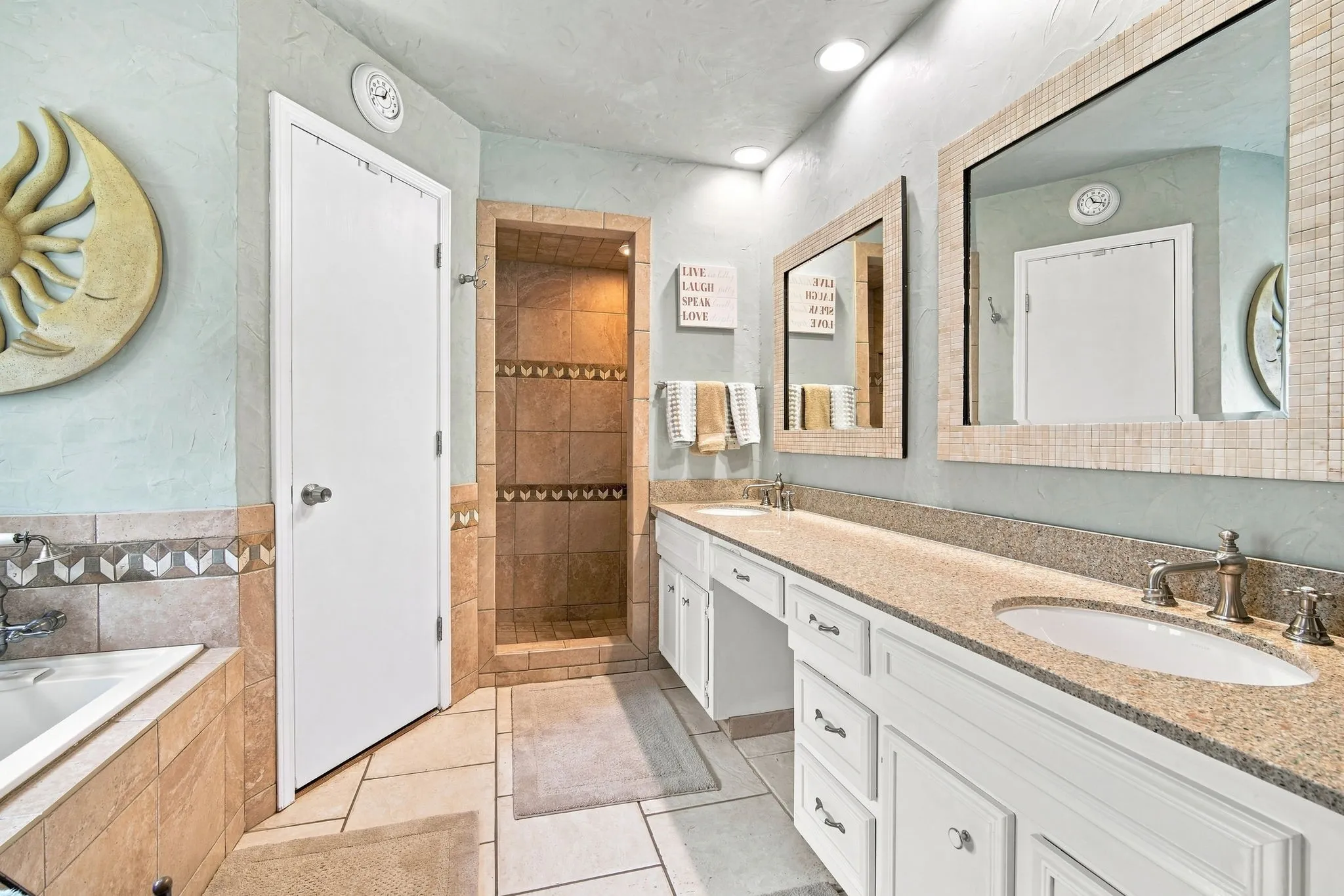 Bathroom featuring a dual vanity with undermount sinks, a built-in shower with tile surround, a built-in tub with tile surround, and tile flooring