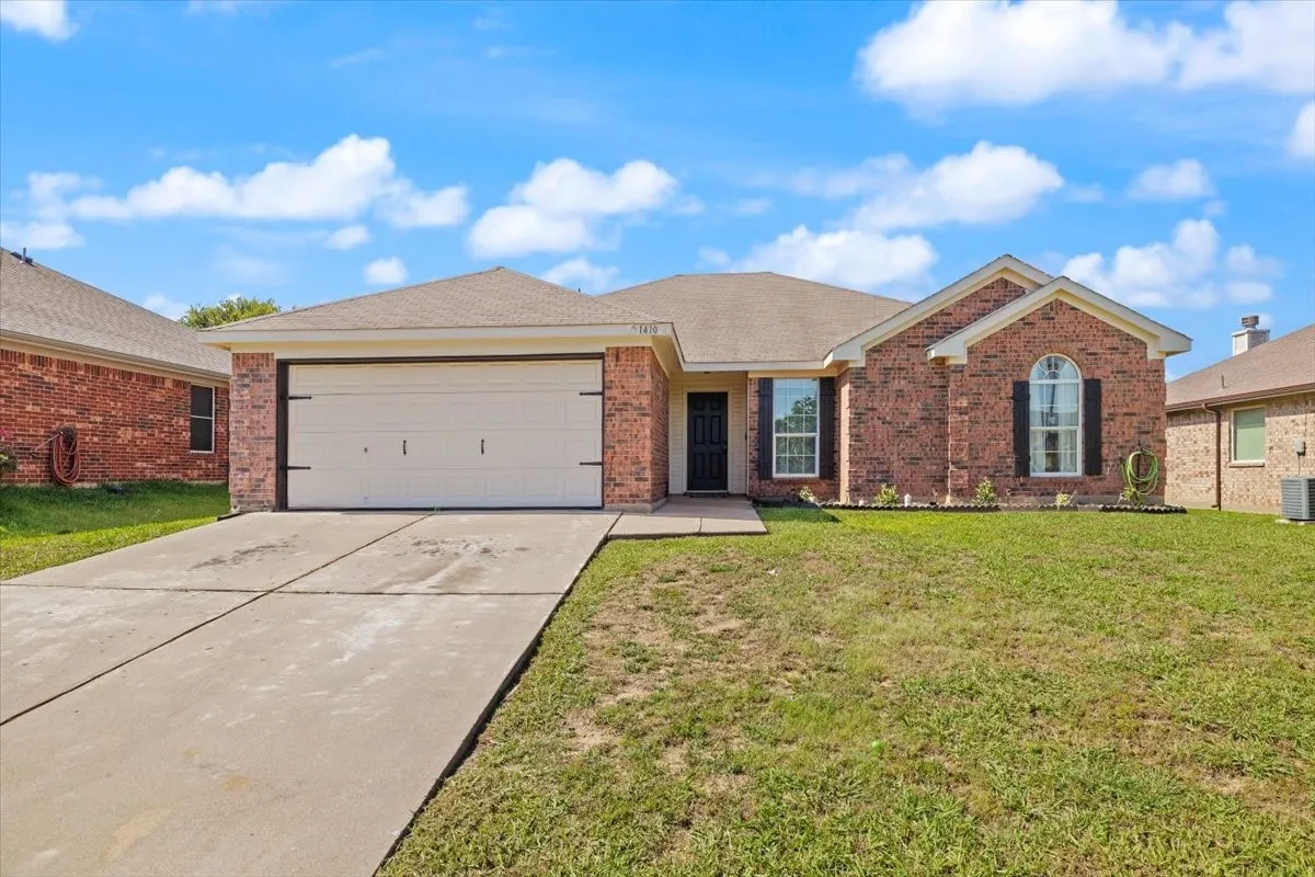 Brick facade home with a two-car garage, concrete driveway, and front lawn