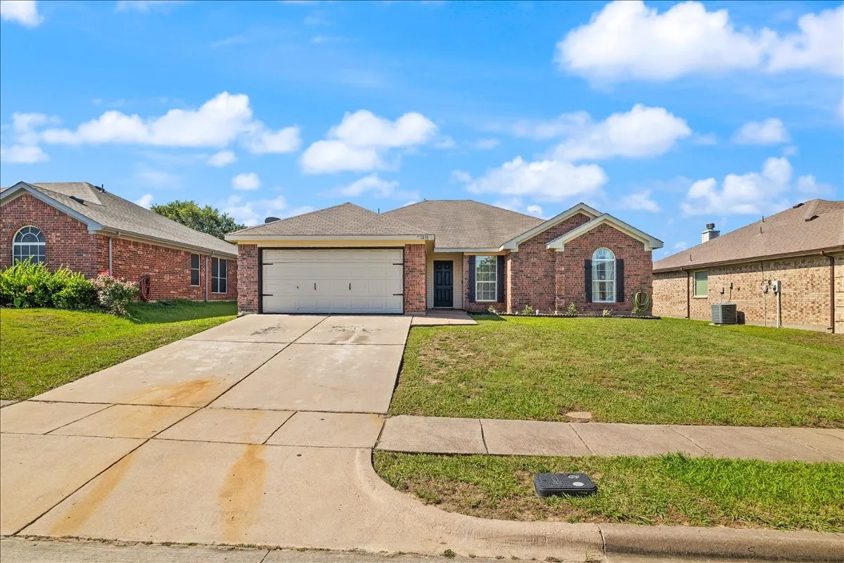 Brick exterior home with an attached two-car garage, concrete driveway, and front lawn