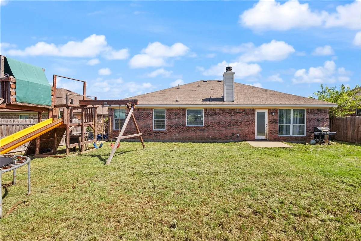 Expansive backyard featuring a red brick exterior, a concrete patio, and a wood privacy fence