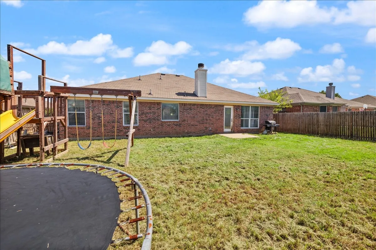 Expansive backyard featuring a brick exterior, a patio area, and a privacy fence