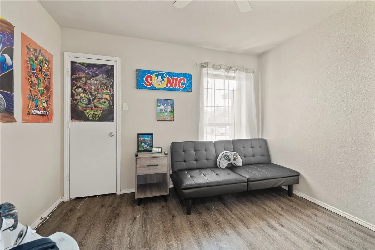 Interior room featuring wood-finish flooring, light-colored walls, and a window with security bars