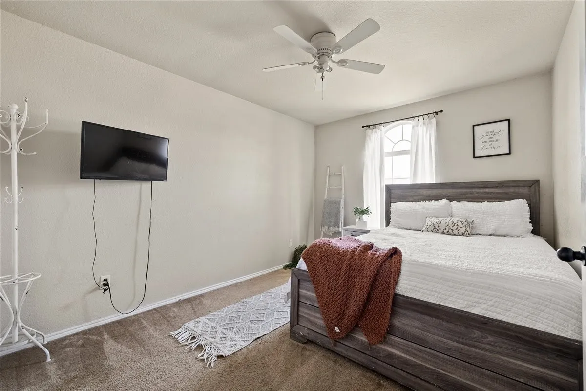 Neutral-toned bedroom featuring wall-to-wall carpeting and a ceiling fan