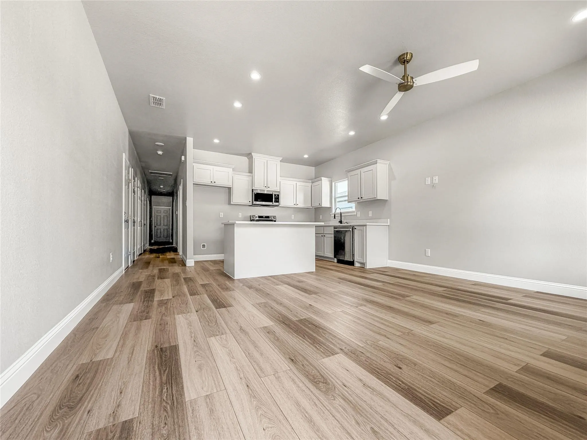 Carpeted room featuring two double-hung windows, a ceiling fan with integrated lighting, recessed ceiling lighting, and a paneled interior door