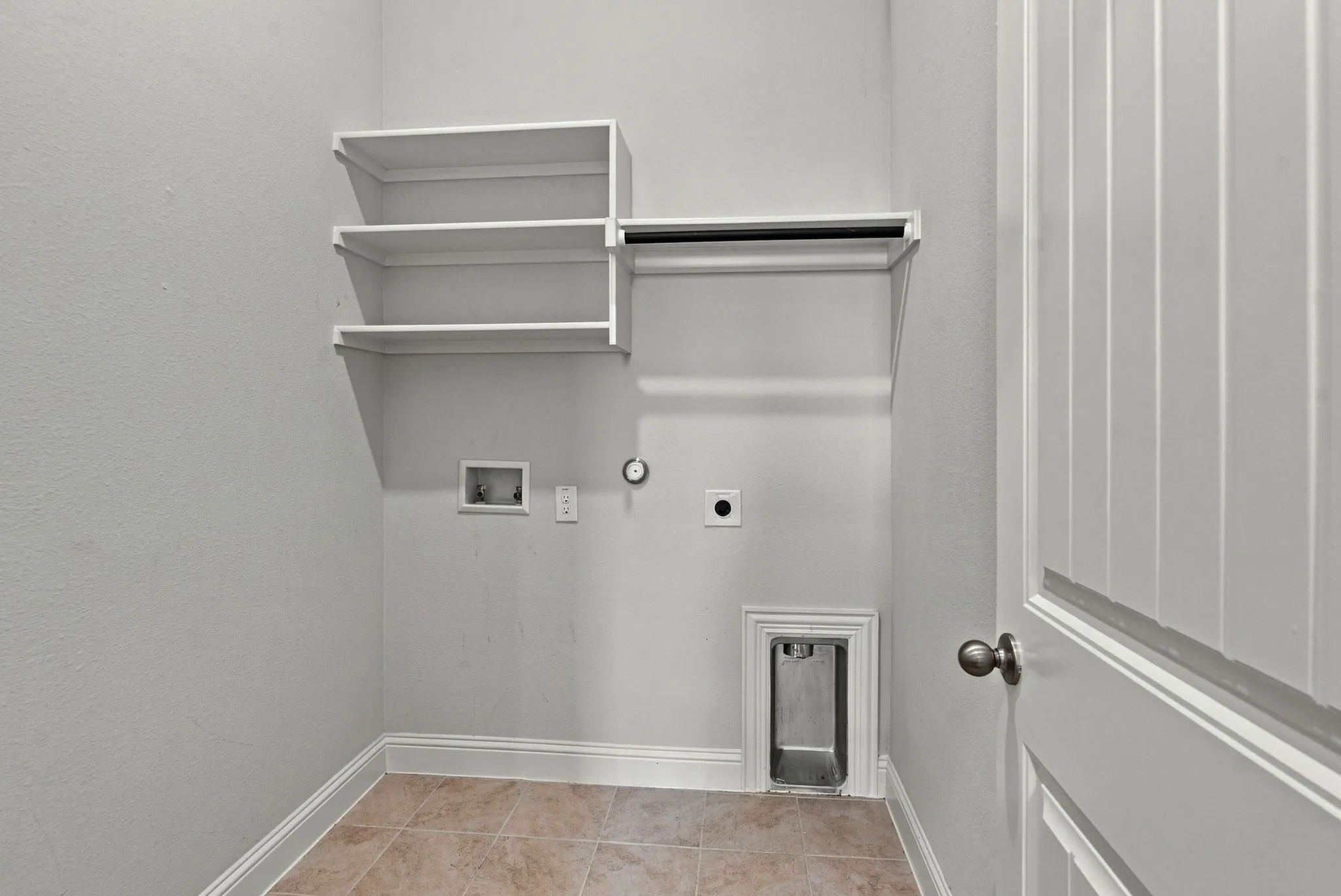 Dedicated laundry area featuring built-in shelving, a hanging rod, tile flooring, and essential utility hookups