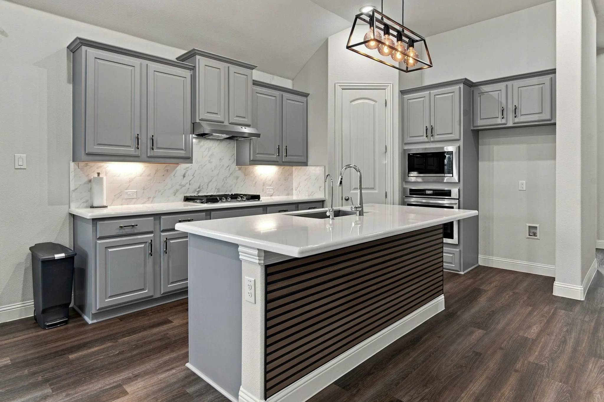 Chef's kitchen featuring gray cabinetry with shaker-style doors, quartz countertops, and a marble subway tile backsplash