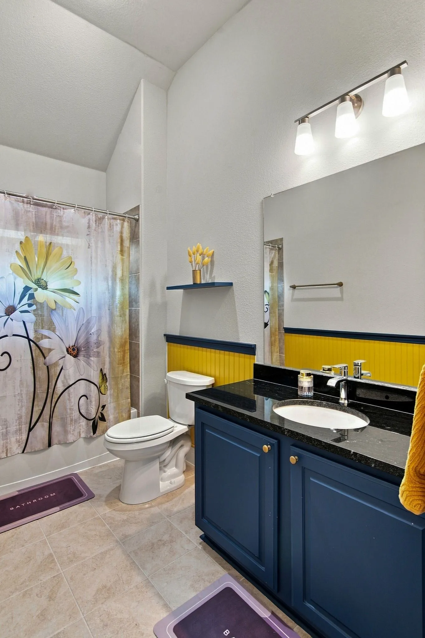 Bathroom featuring a dark blue vanity with a polished countertop, a built-in sink, and a wall-mounted mirror