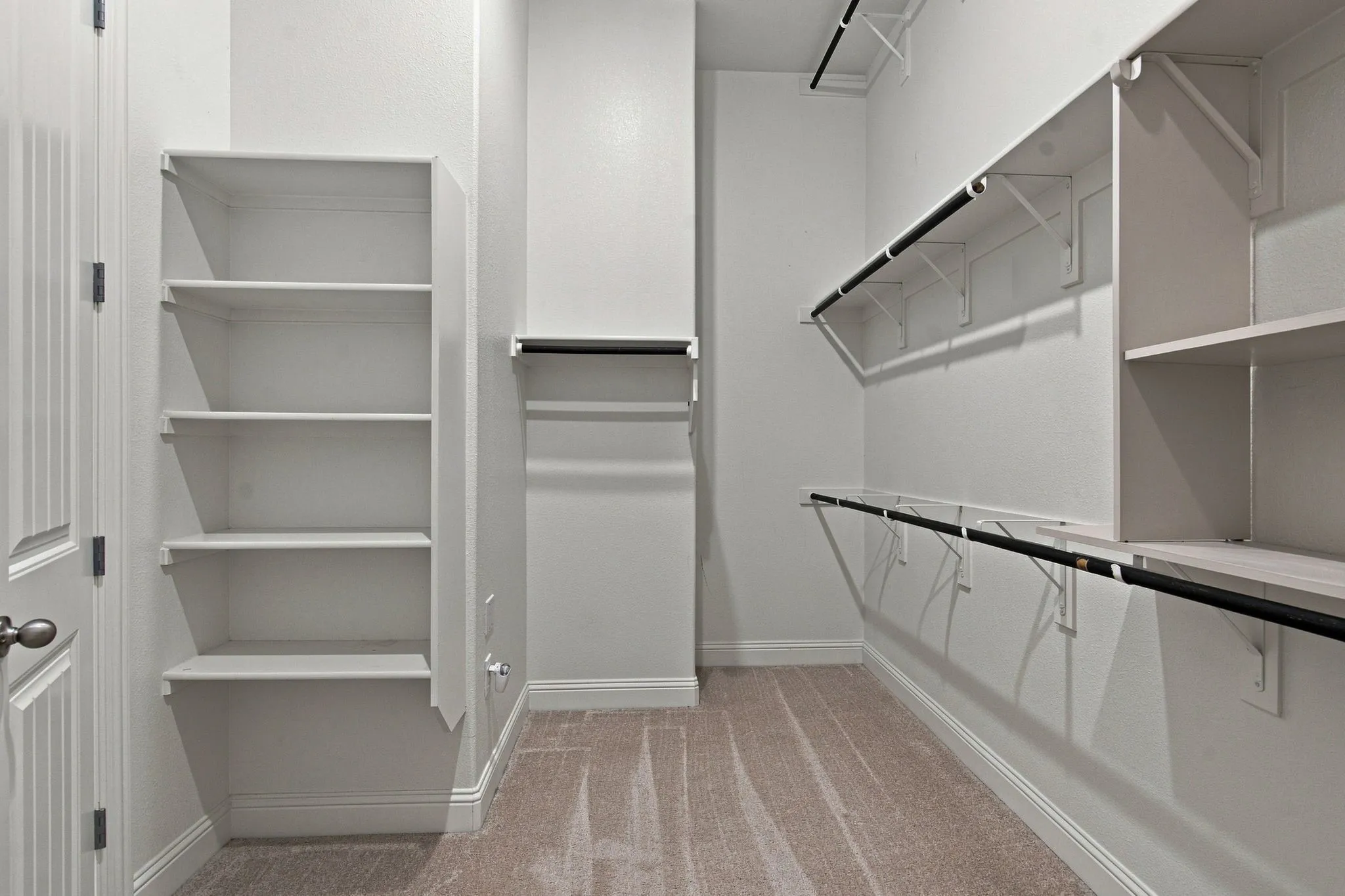Walk-in closet featuring built-in shelving, multiple hanging rods, and neutral-toned carpeting