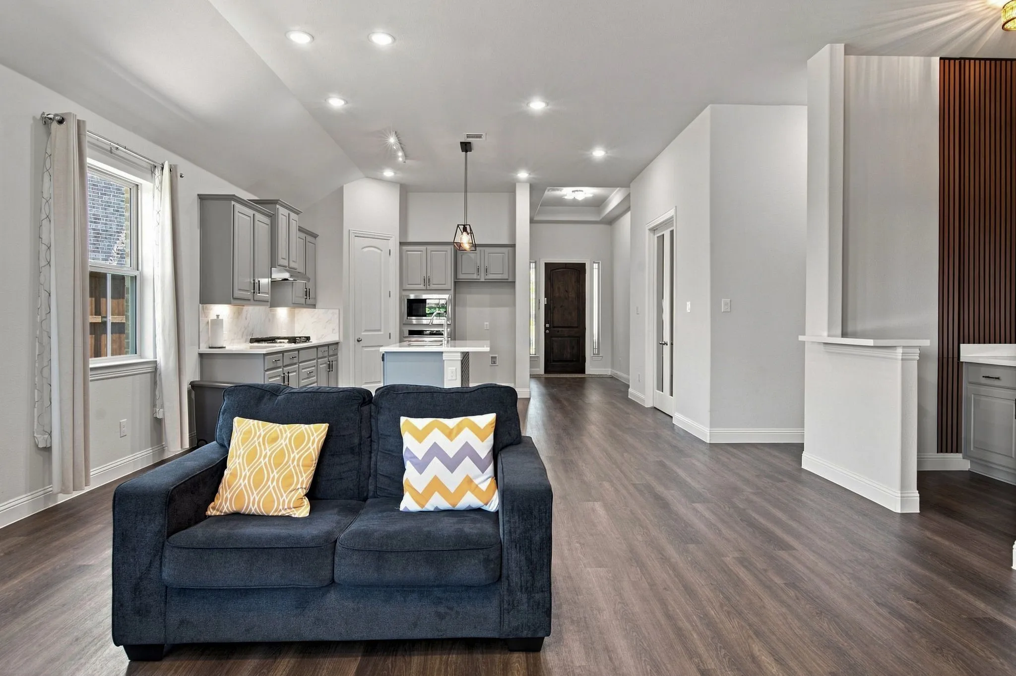 Open-concept living space featuring wood-finish flooring, recessed lighting, and a kitchen with gray cabinetry