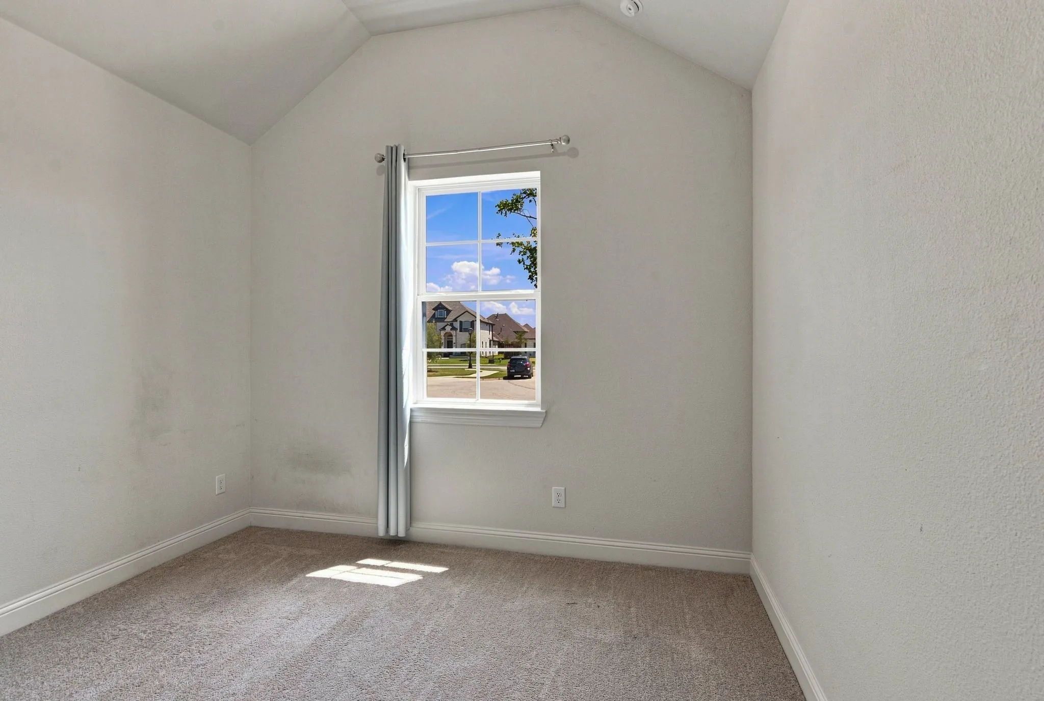 Bright room featuring a vaulted ceiling and a double-hung window
