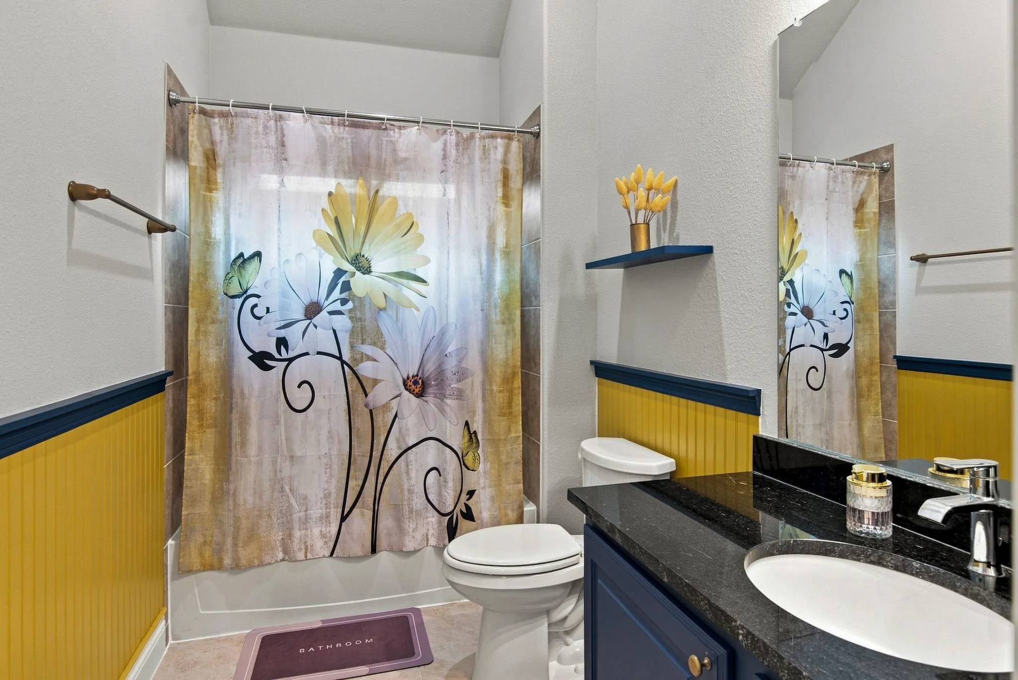 Bathroom featuring a shower-tub combination, a dark granite-style countertop, a white oval undermount sink, and a navy blue vanity cabinet