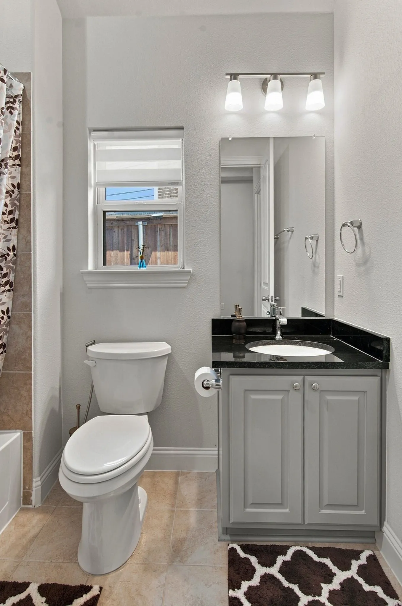 Bathroom featuring a gray vanity with a dark countertop, an undermount sink, and a framed mirror