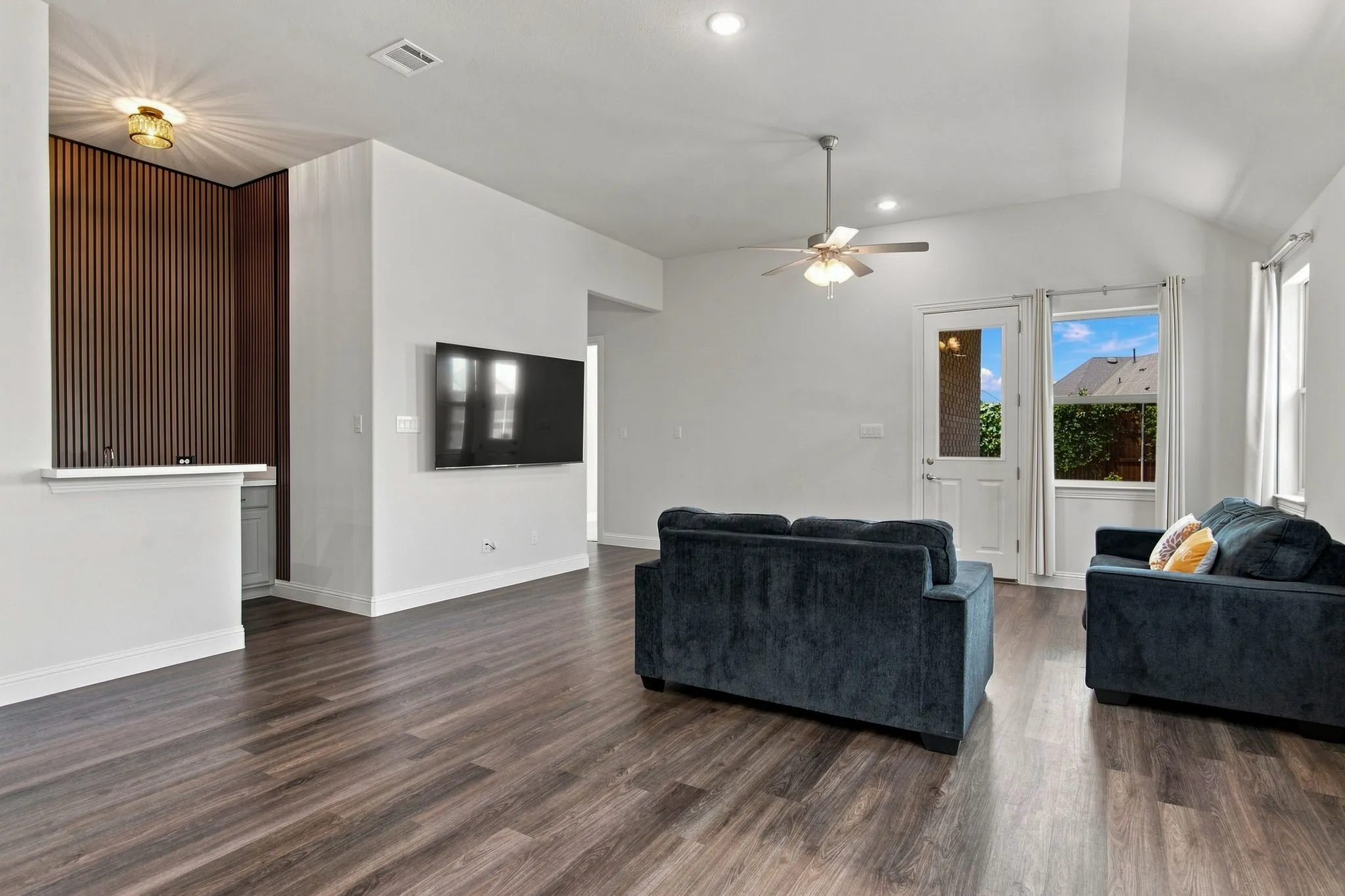 Spacious living area featuring wood-finish flooring, recessed lighting, and a vaulted ceiling with a ceiling fan