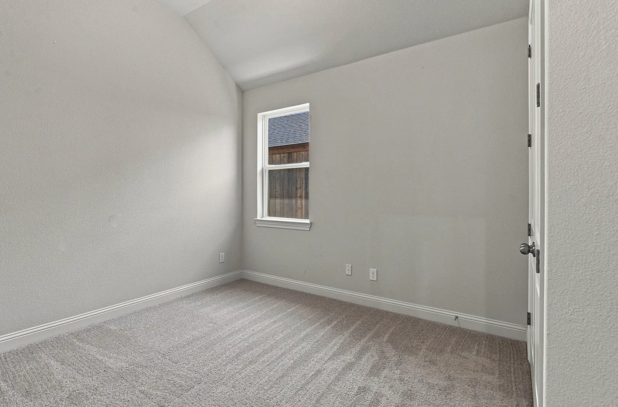 Neutral gray walls featuring an angled ceiling and textured carpeting