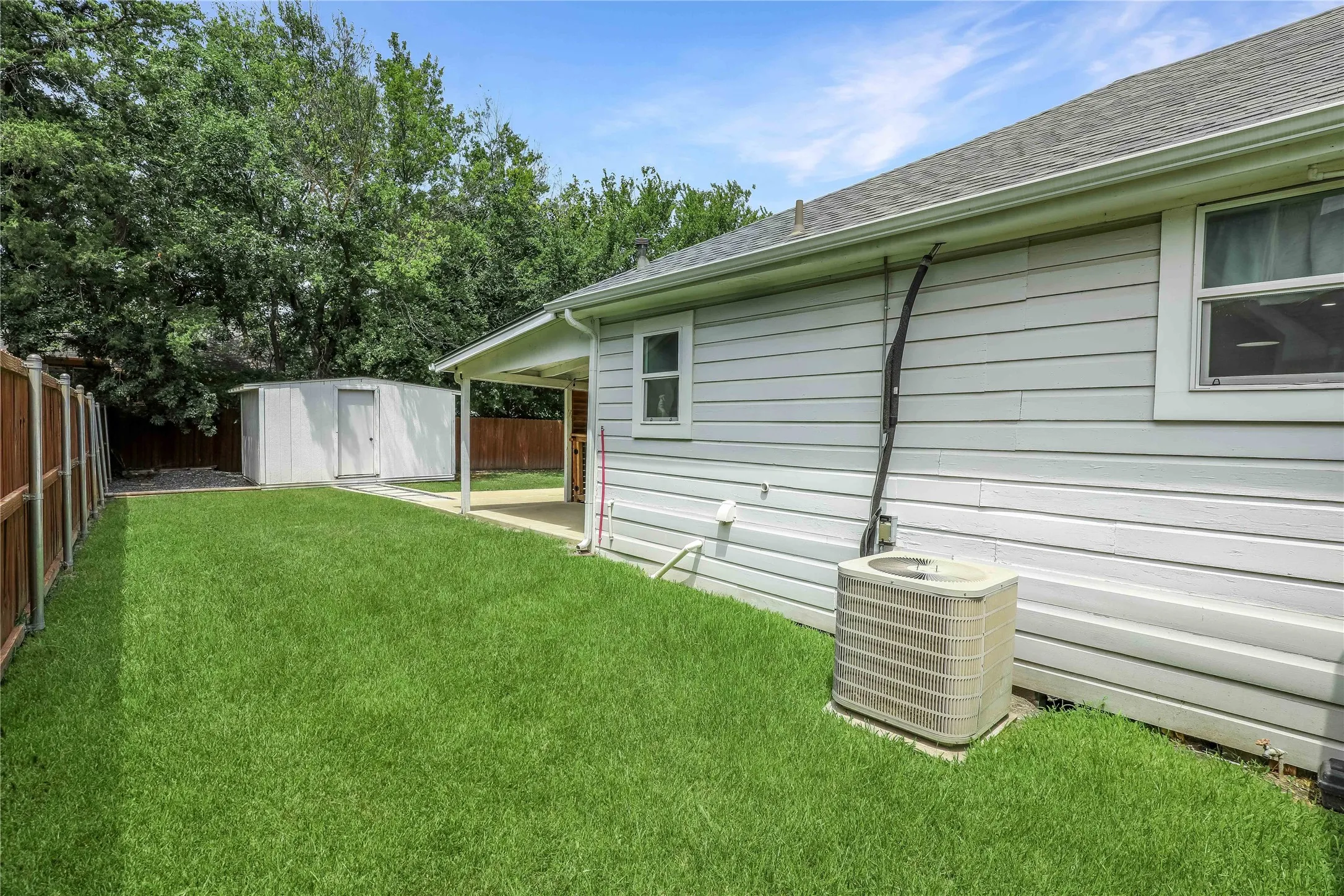Side yard featuring an outdoor storage shed, a covered patio, and a wood privacy fence
