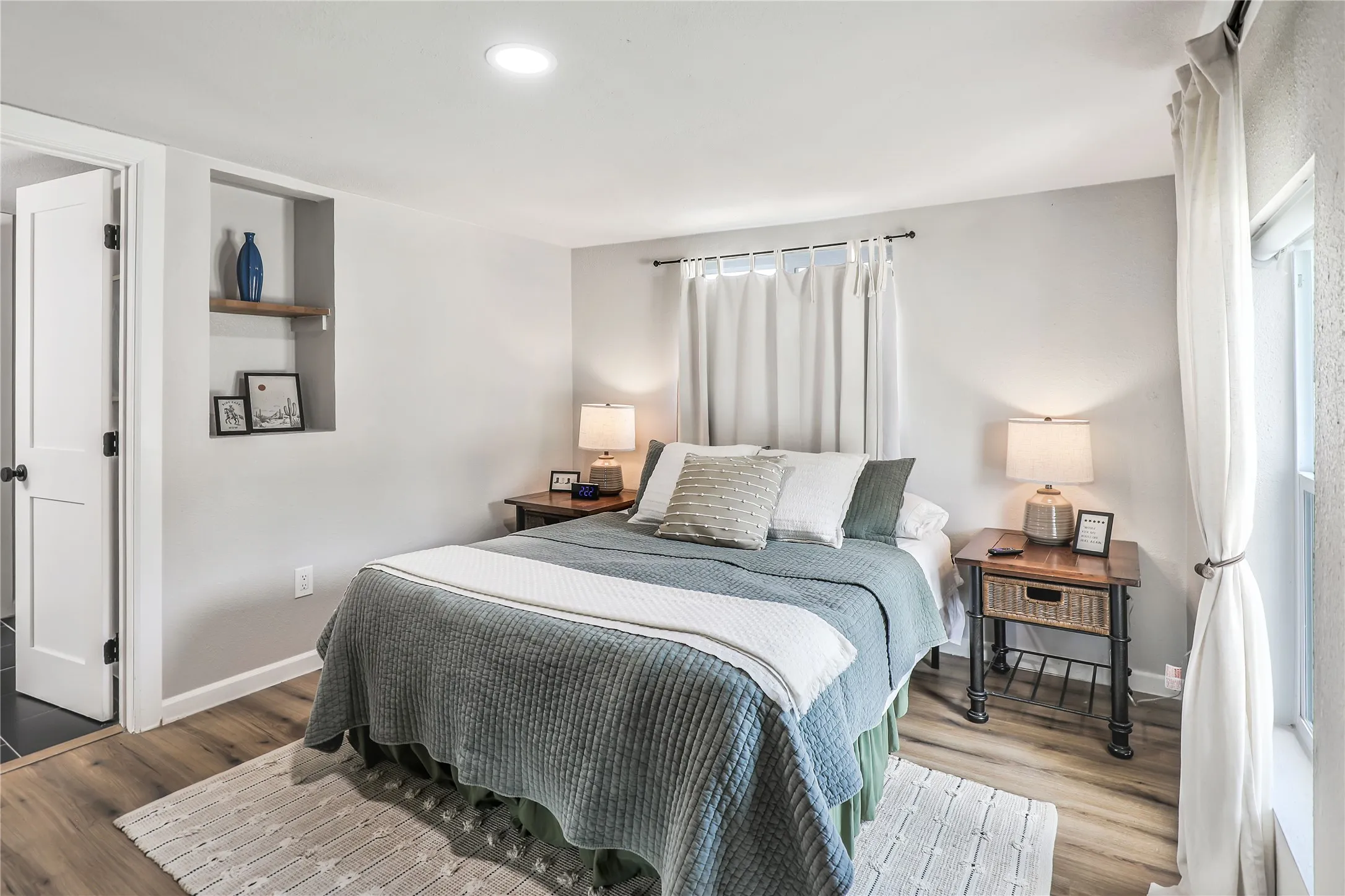 Bedroom featuring wood-finish flooring, recessed lighting, and a built-in wall niche with a wooden shelf