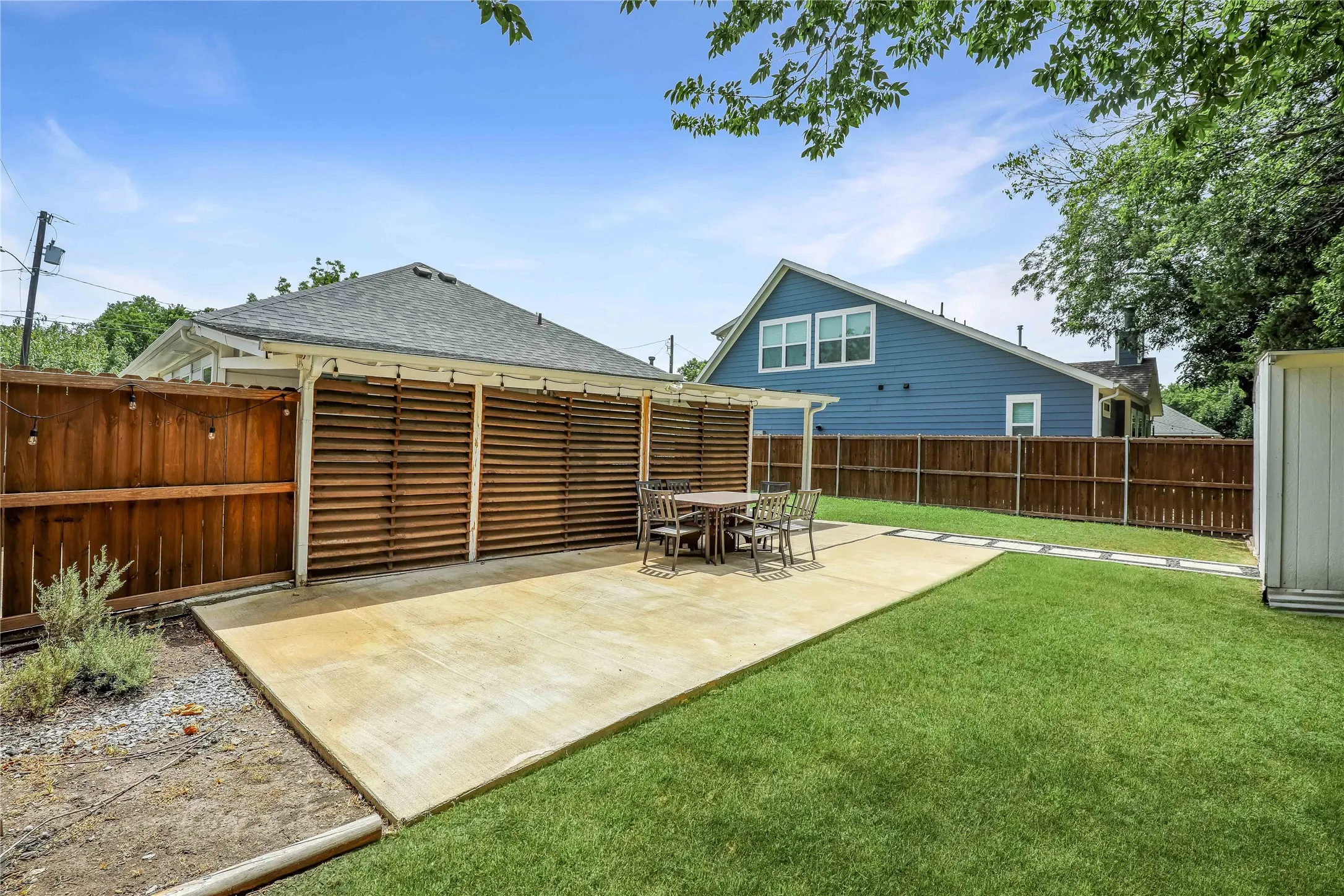 Expansive backyard featuring a concrete patio, a section of manicured lawn, and a wood fence