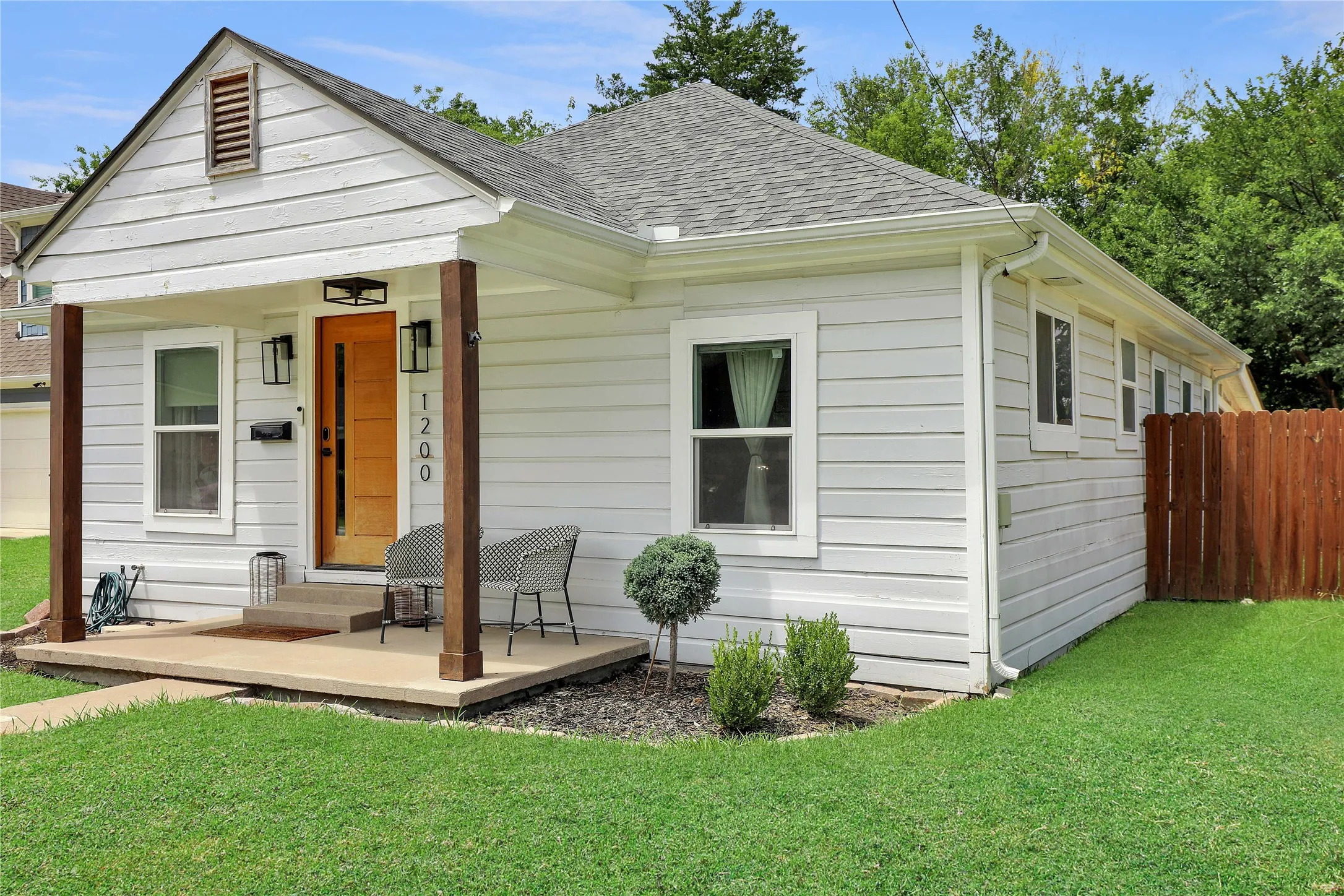 Classic bungalow exterior featuring white horizontal siding and a dark gray shingle roof