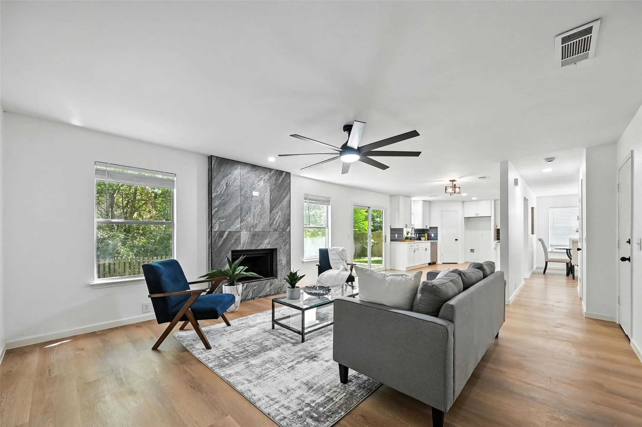 Living area with a high end fireplace, light wood-style floors, ceiling fan, and recessed lighting