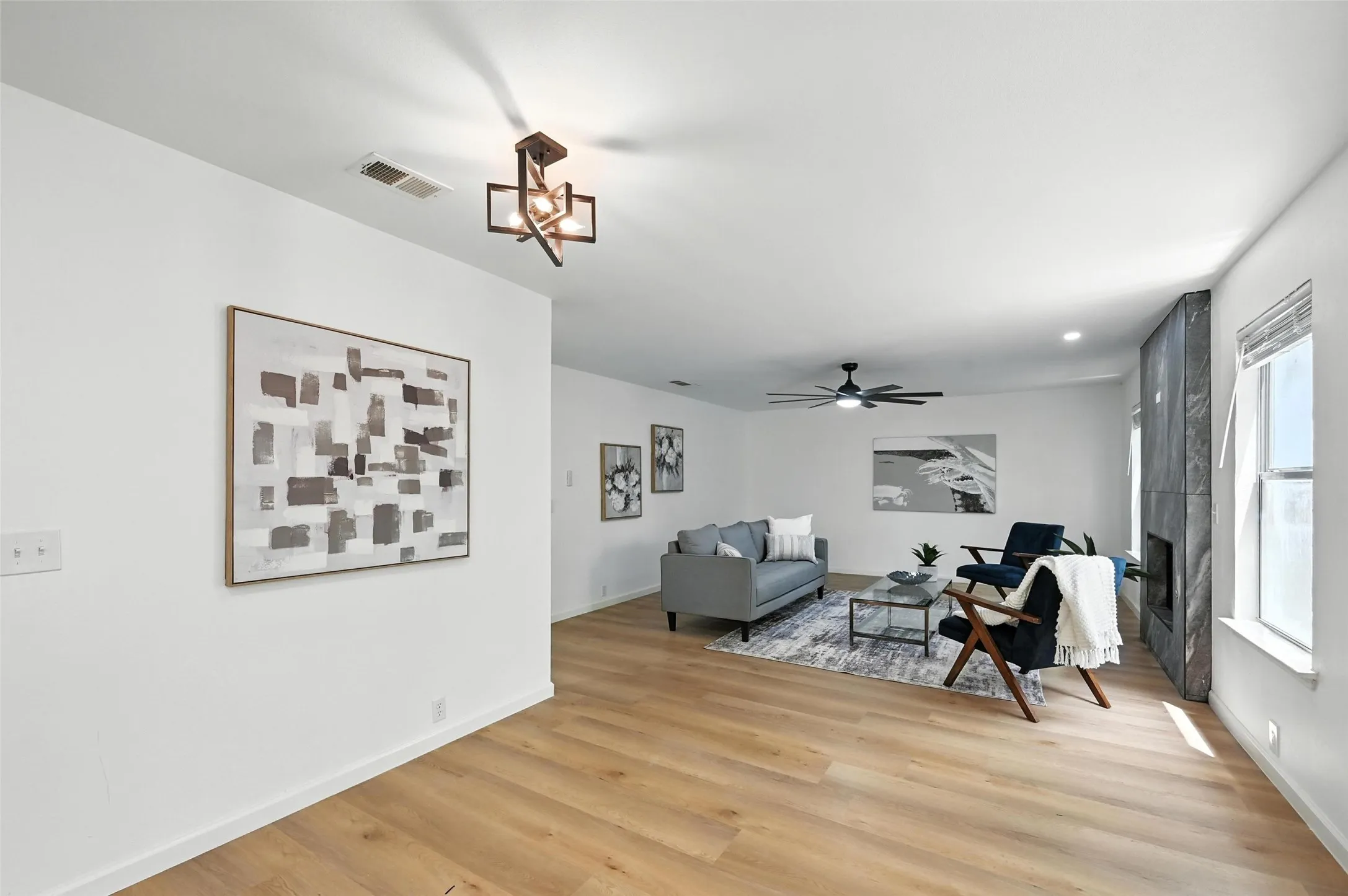 Living room featuring light wood-style floors, a ceiling fan, and a chandelier