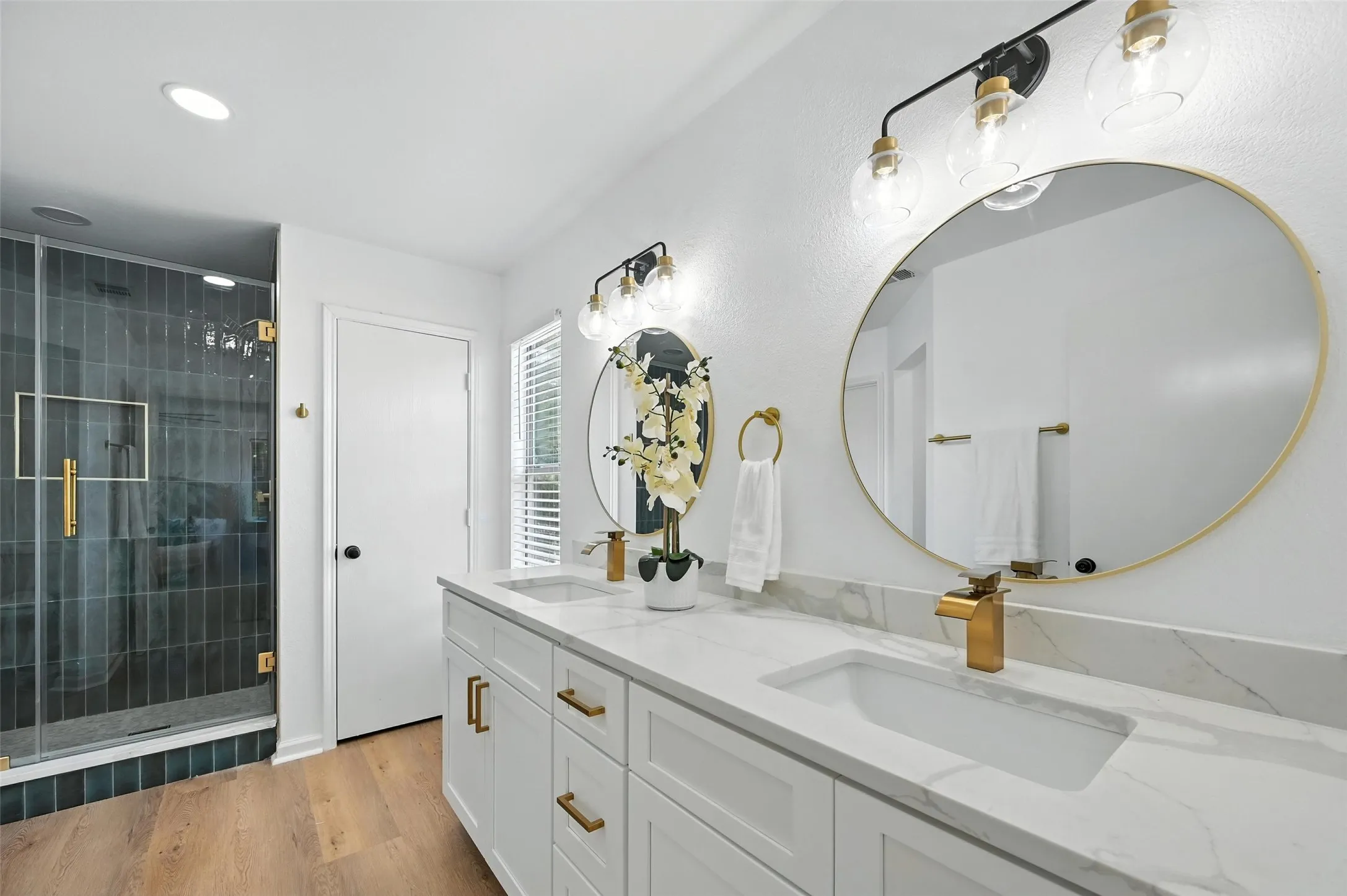 Bathroom featuring double vanity, a shower stall, wood finished floors, and recessed lighting