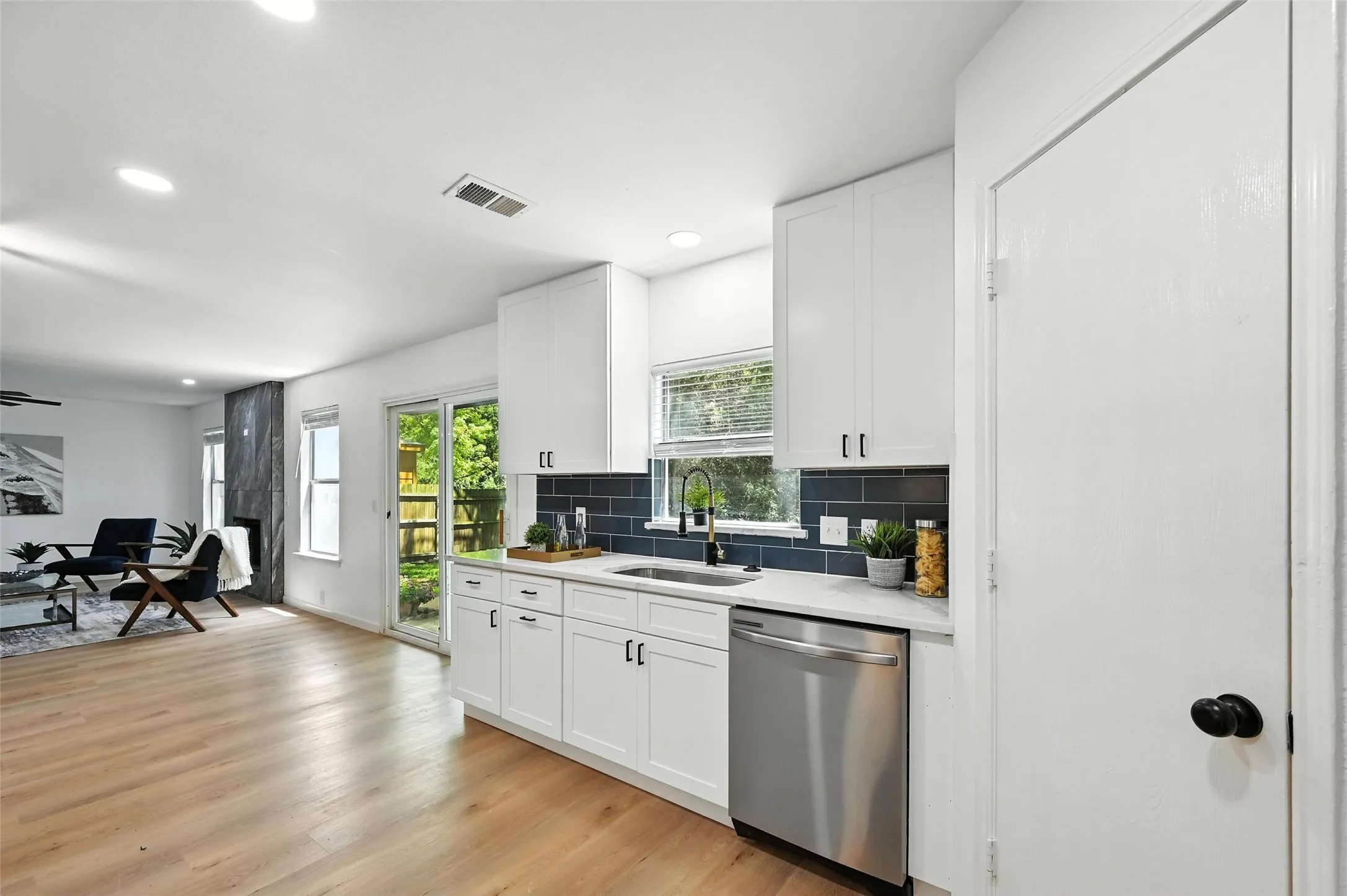 Kitchen featuring stainless steel dishwasher, light countertops, backsplash, white cabinets, and recessed lighting