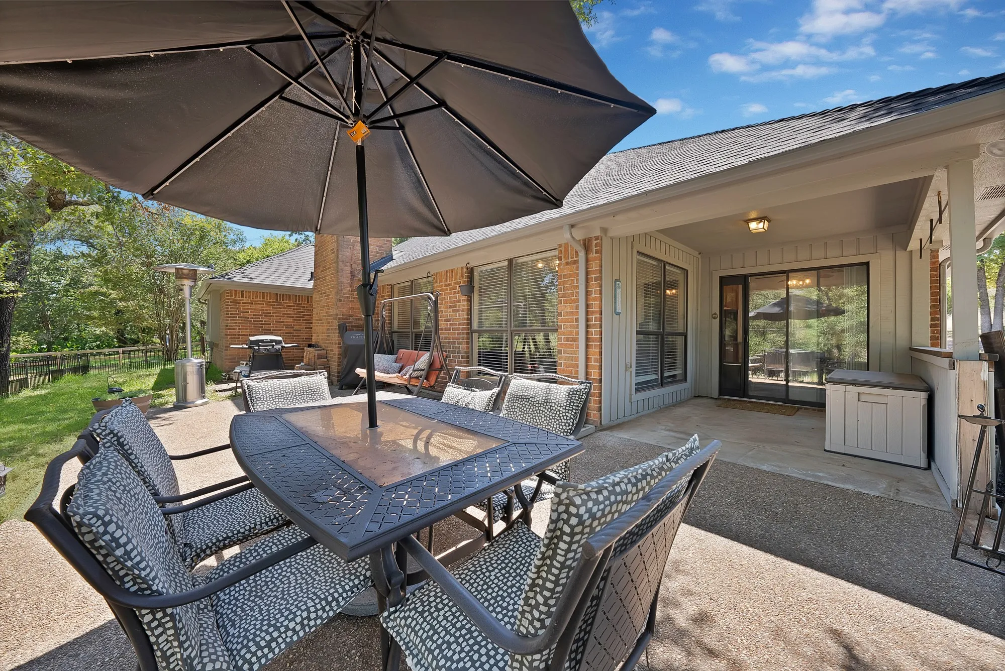 Expansive outdoor patio with a covered area, brick exterior, and multiple large windows