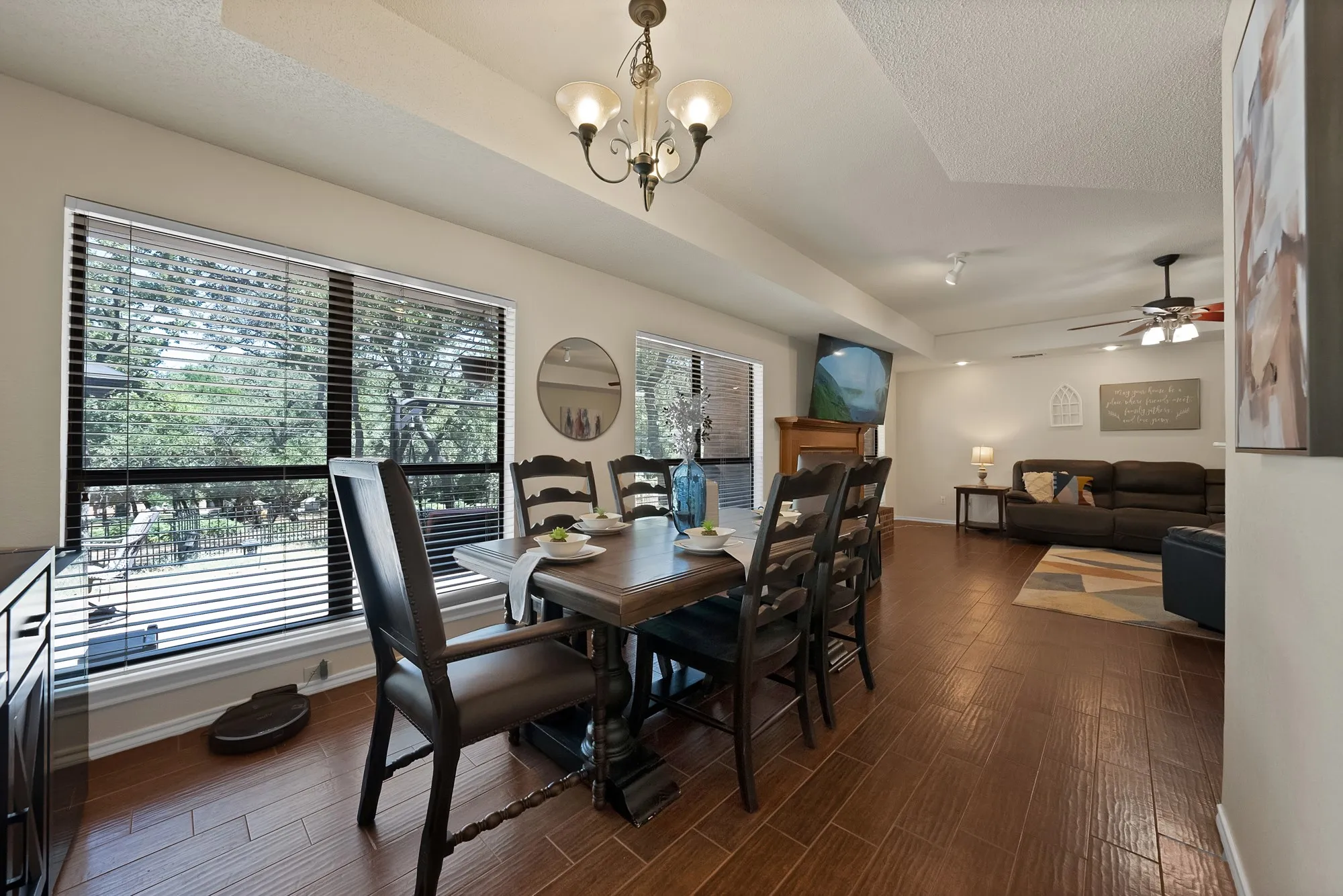 Spacious dining area with wood-finish flooring, large windows, and a classic chandelier