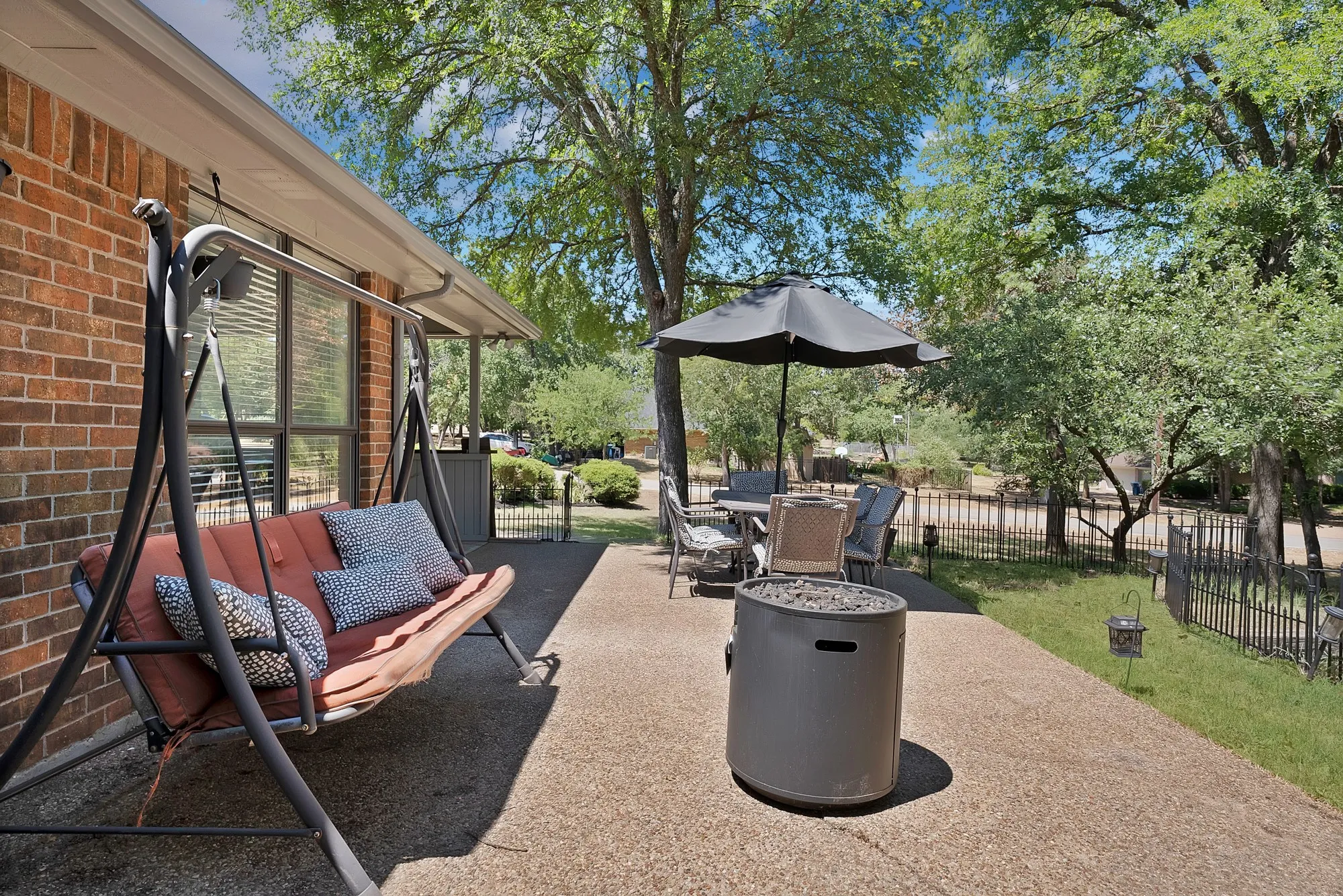 Expansive concrete patio with a brick exterior, offering a covered area and a fenced yard