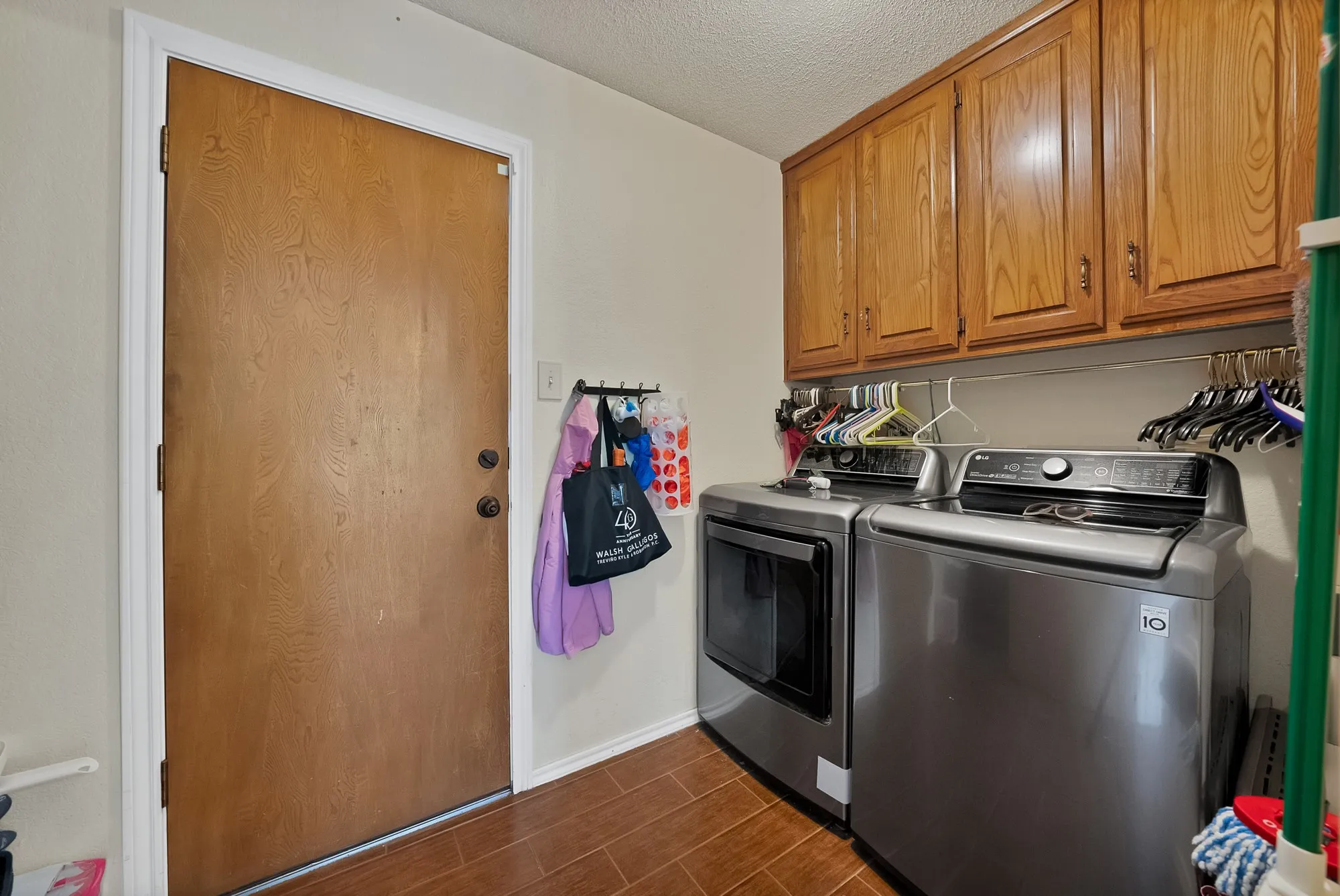 Laundry area with wood-finish flooring, built-in cabinetry, and a wood-finish door