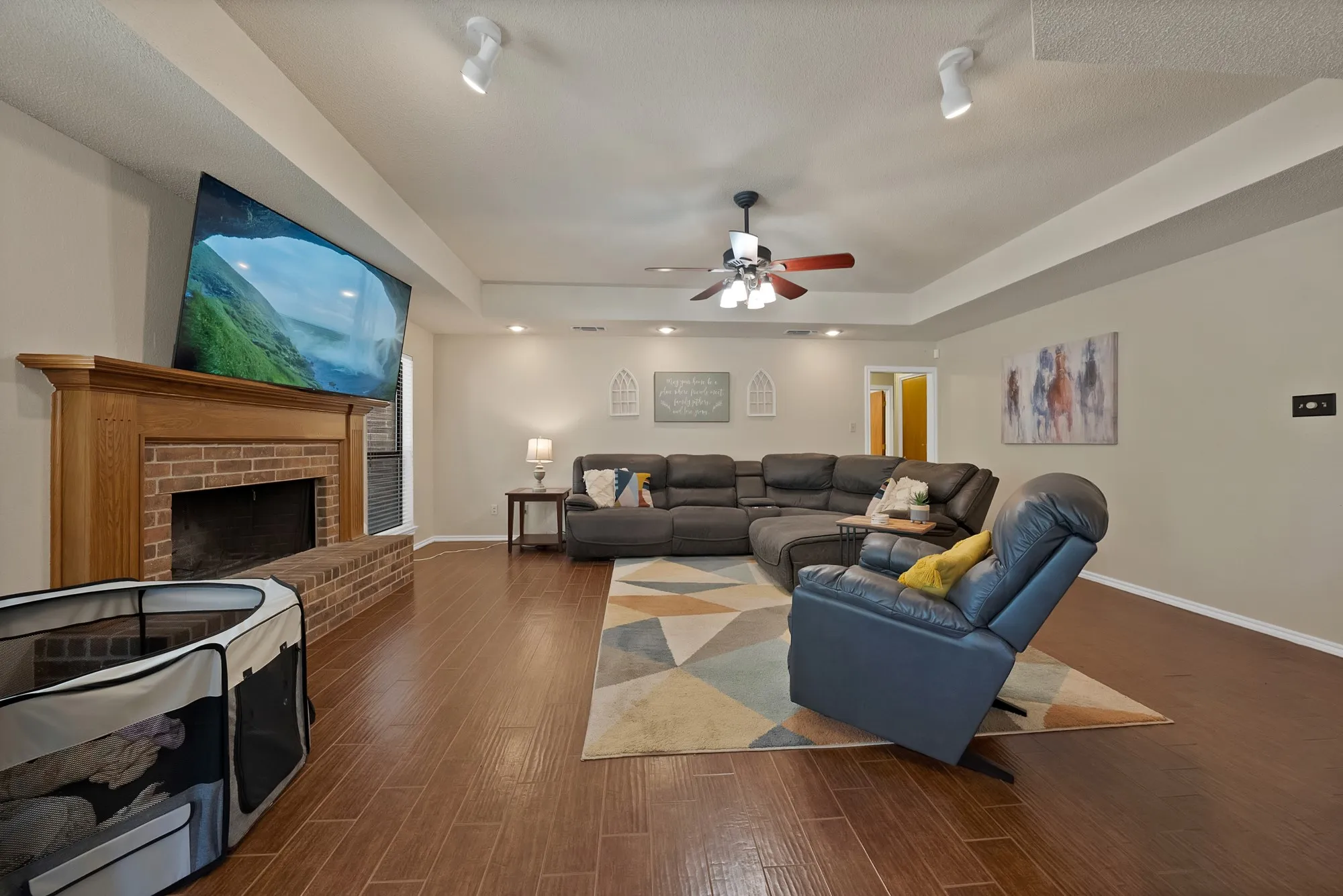 Living area featuring wood-finish flooring, brick fireplace with wood mantel, recessed lighting, and a ceiling fan