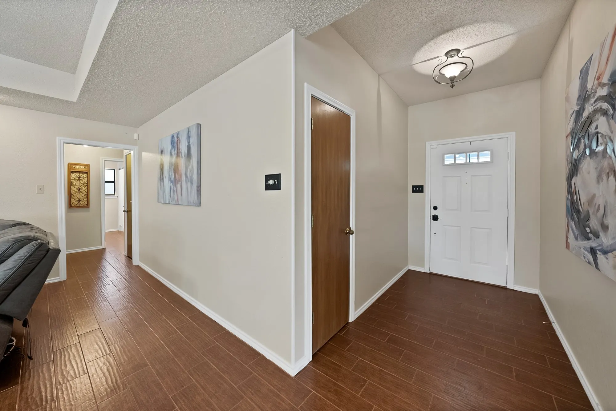 Wood-look flooring throughout, white paneled door with glass inserts, and a decorative ceiling light fixture