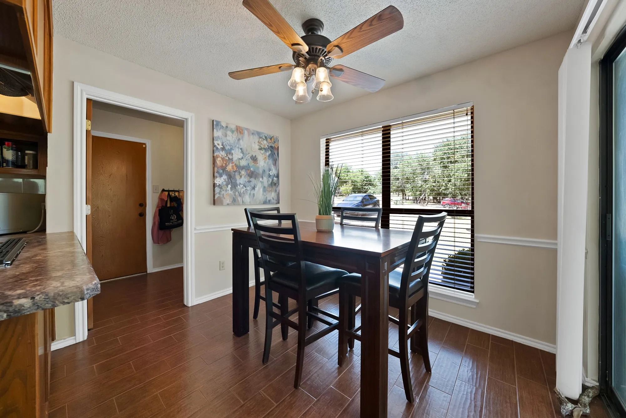 Wood-finish flooring, ceiling fan with integrated lighting, window with blinds, and decorative trim molding