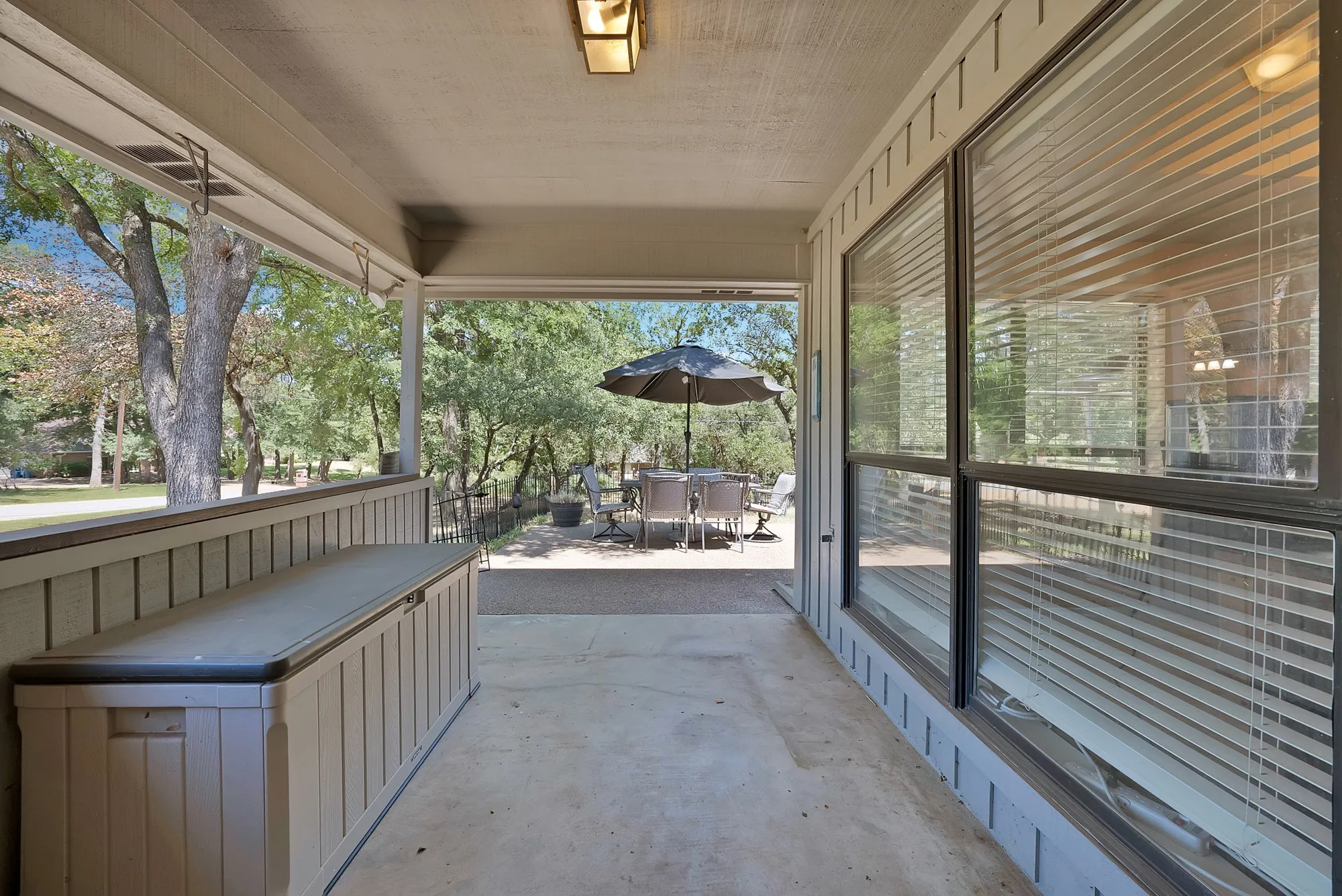 Covered outdoor patio with a concrete surface, featuring a fixed outdoor light fixture and exterior wall paneling