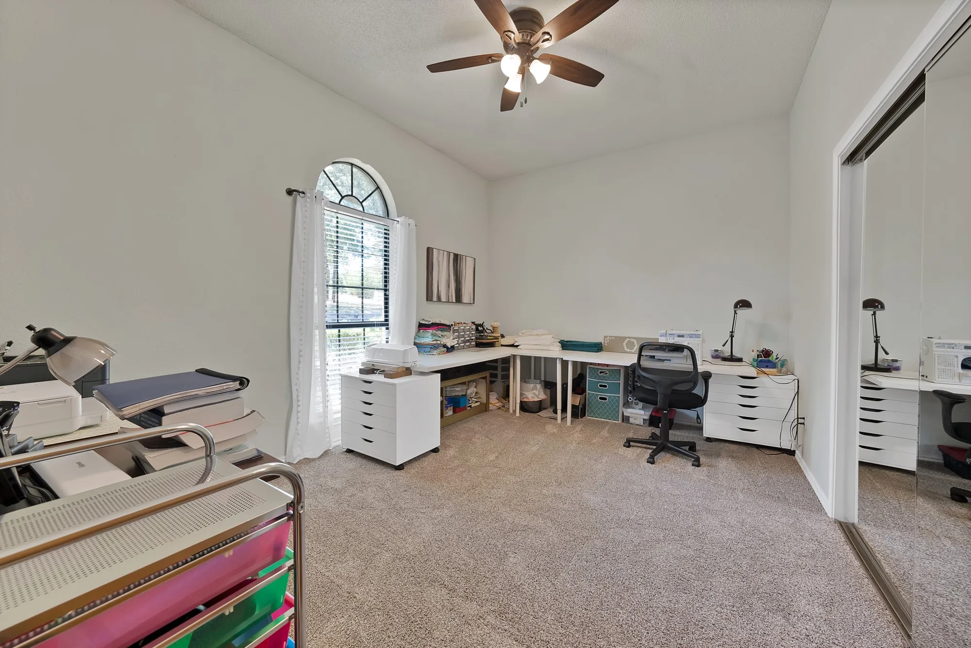 Vaulted ceiling with a ceiling fan, arched window with blinds, wall-to-wall carpeting, and mirrored closet doors