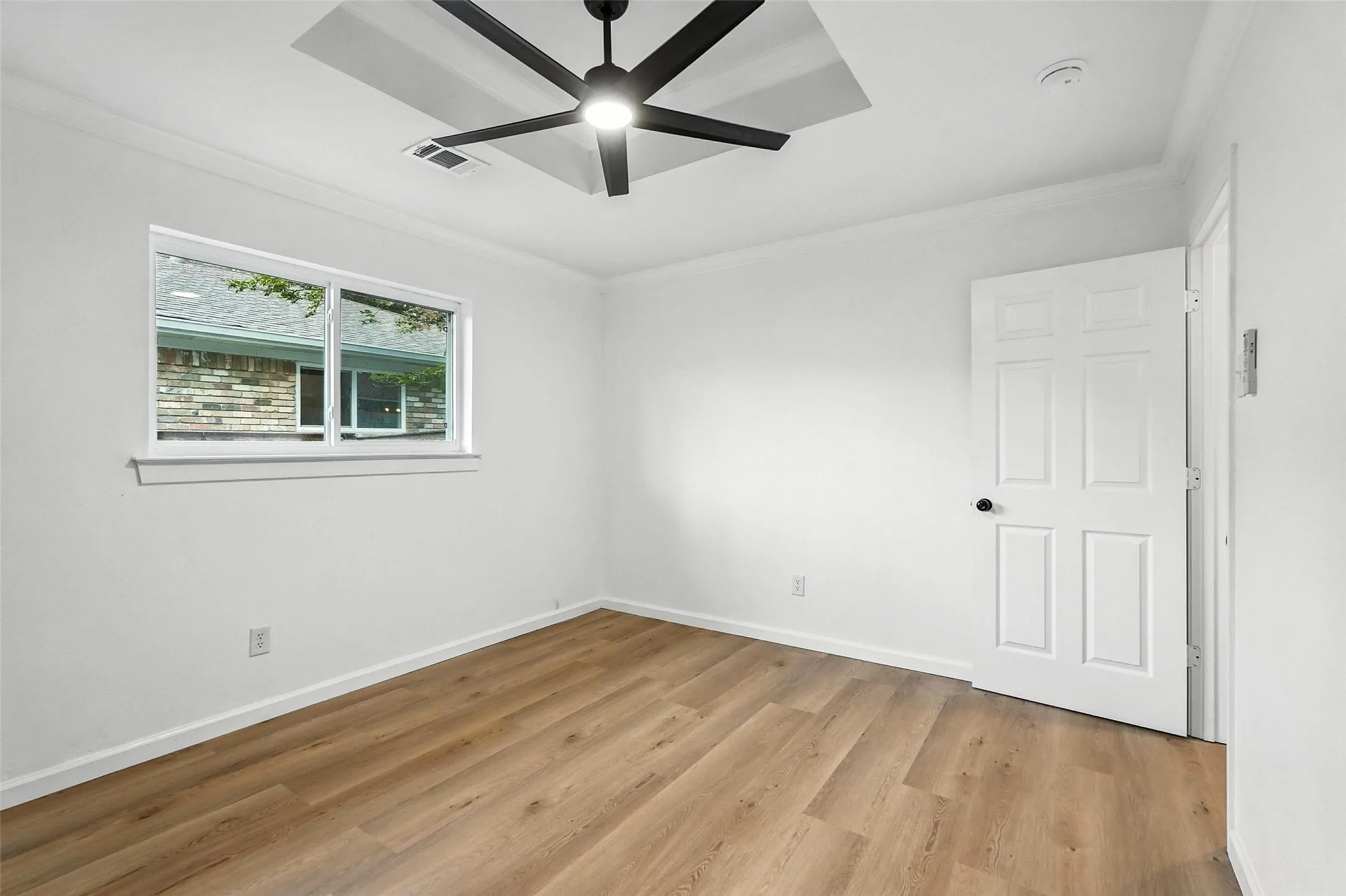 Unfurnished room with crown molding, light wood-style flooring, and a ceiling fan