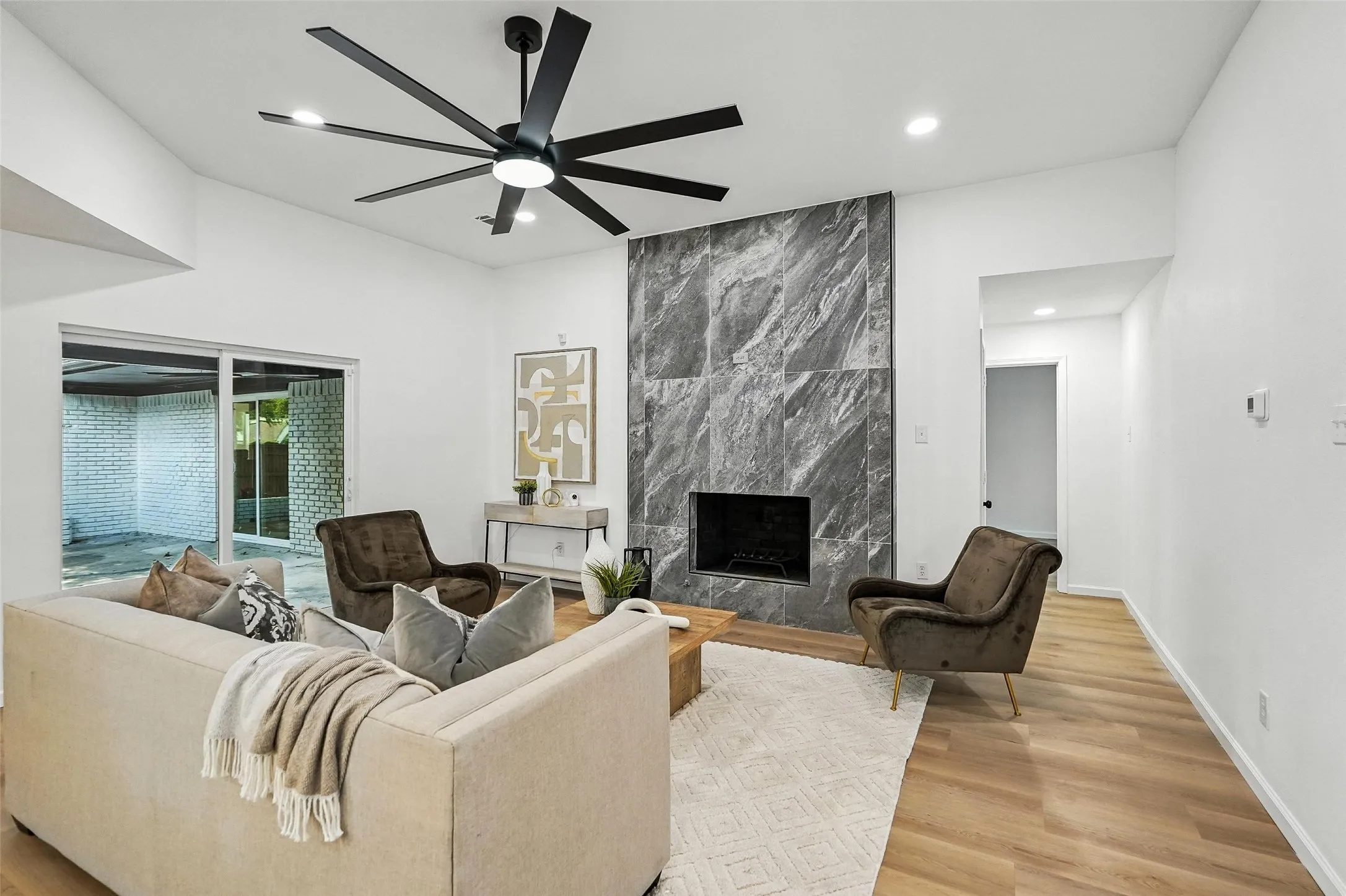 Living room with a fireplace, light wood-style floors, ceiling fan, and recessed lighting